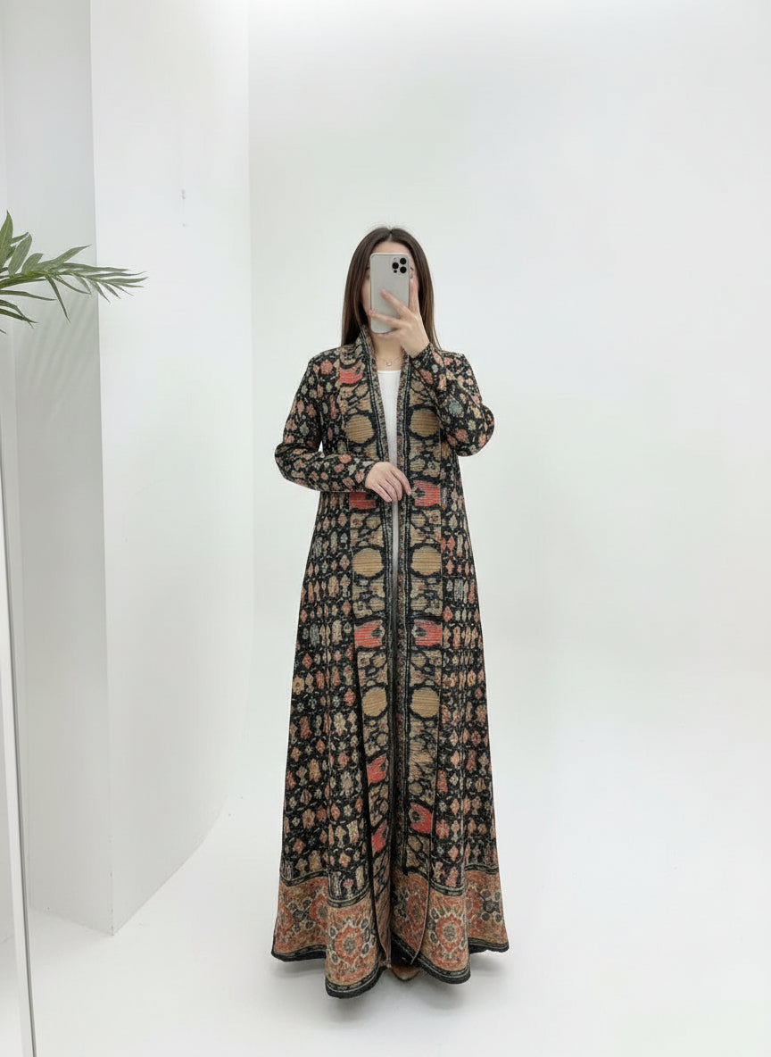 Person wearing a long, patterned coat against a white background. Al Noor Pleated Abaya Multi – 2025 Dubai Edition (عباءة النور بليت – إصدار دبي 2025) - Noor & Grace