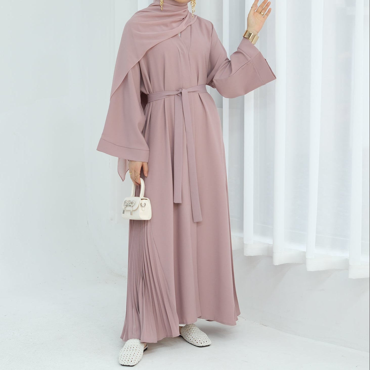 Woman wearing a black abaya against a white background. Abaya Al-Tayyat Al-Aneeqa (عباءة الطيات الأنيقة) - Noor & Grace