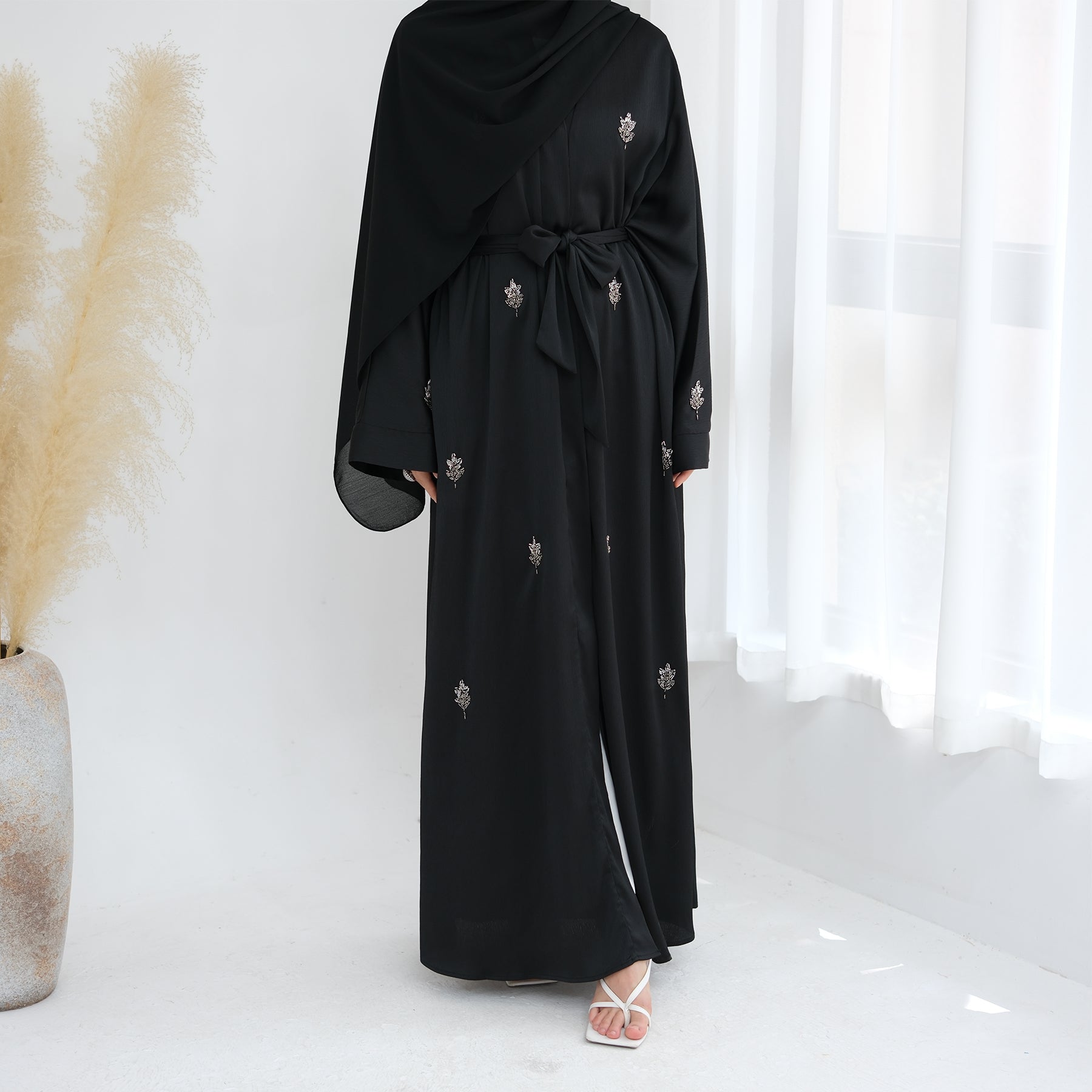 Black abaya with floral embroidery on a white background. Abaya_Awrak_Al-Anaaqa_Back- Noor & Grace