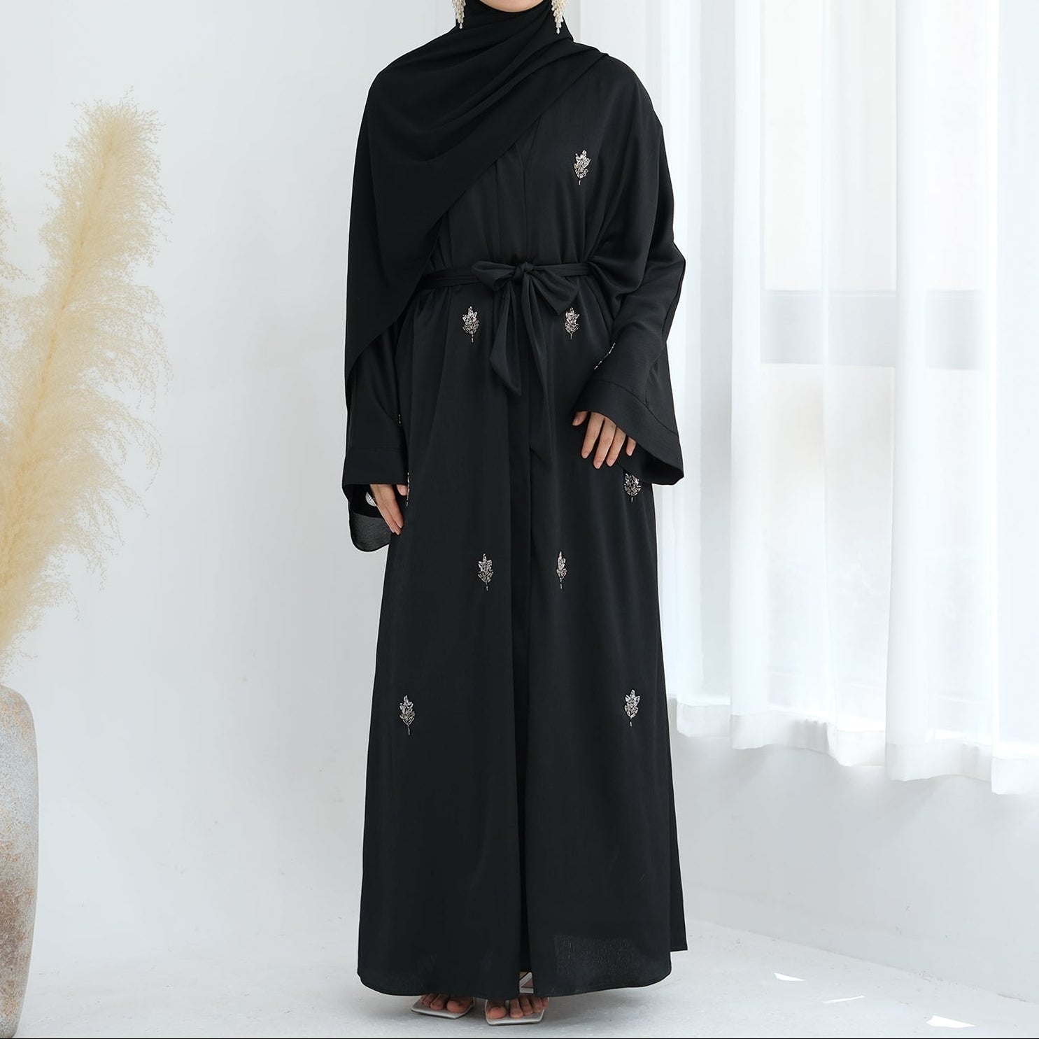 Black abaya with floral embroidery on a white background. Abaya_Awrak_Al-Anaaqa_Back- Noor & Grace