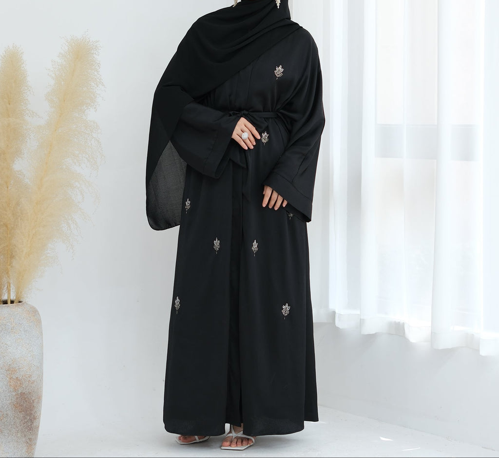 Black abaya with floral embroidery on a white background. Abaya_Awrak_Al-Anaaqa_Back- Noor & Grace