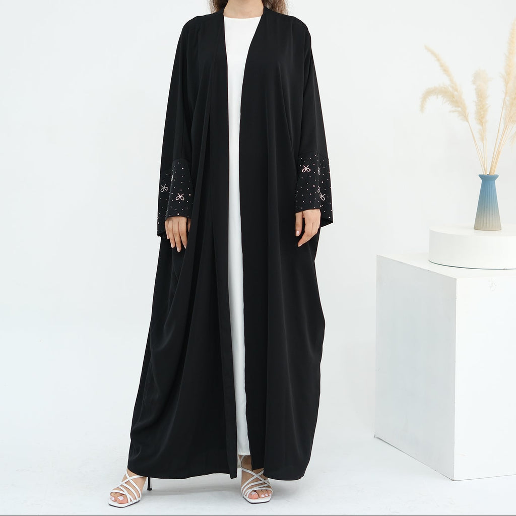 Woman wearing a black abaya with white stripes on a white background. AlLayaliEmbroideredOpenAbaya_Noor_GraceBlack1