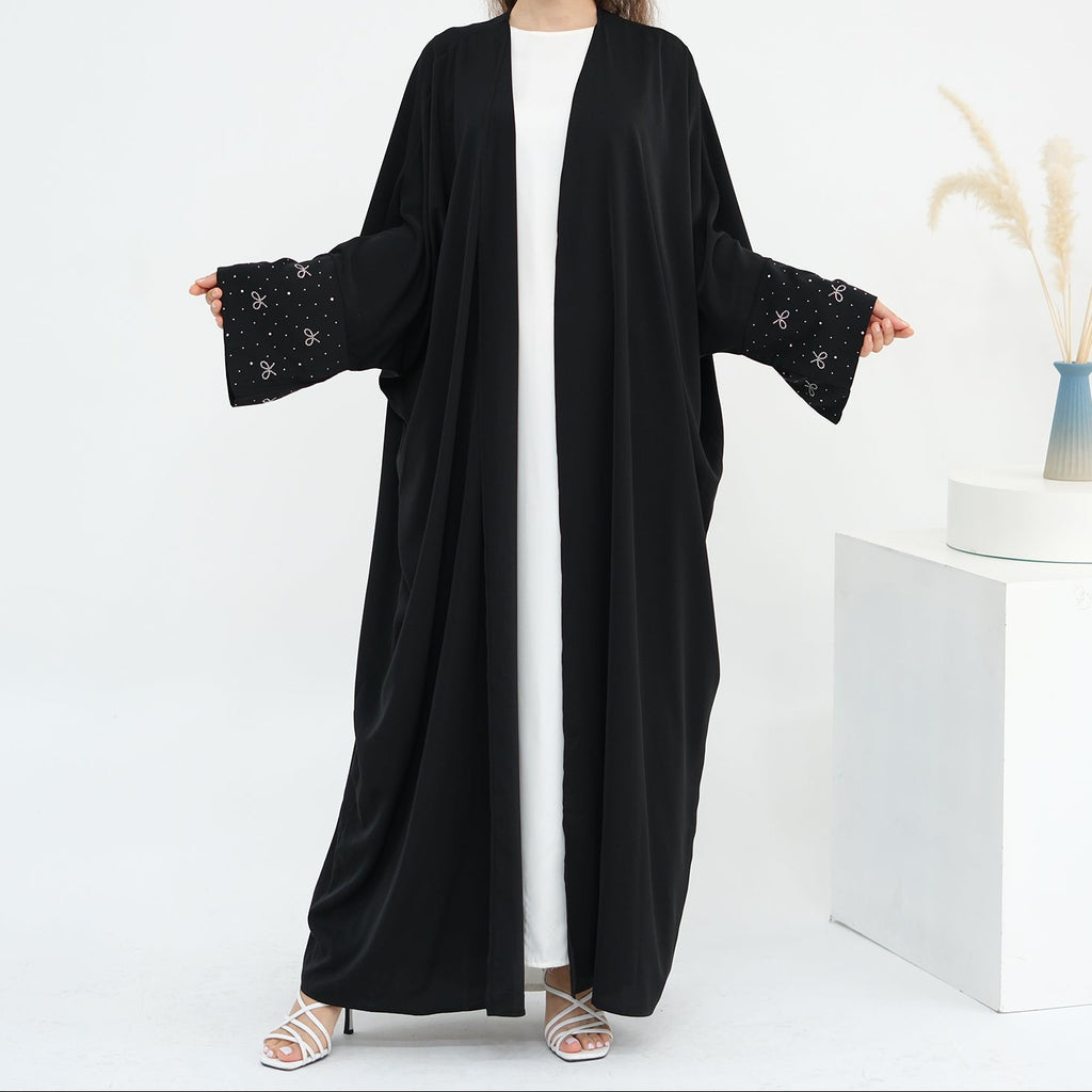 Woman wearing a black abaya with white background. AlLayaliEmbroideredOpenAbaya_Noor_GraceBlack2