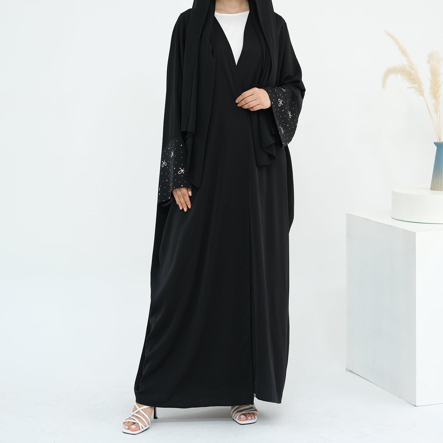 Woman wearing a black abaya with white background. AlLayaliEmbroideredOpenAbaya_Noor_GraceBlack3
