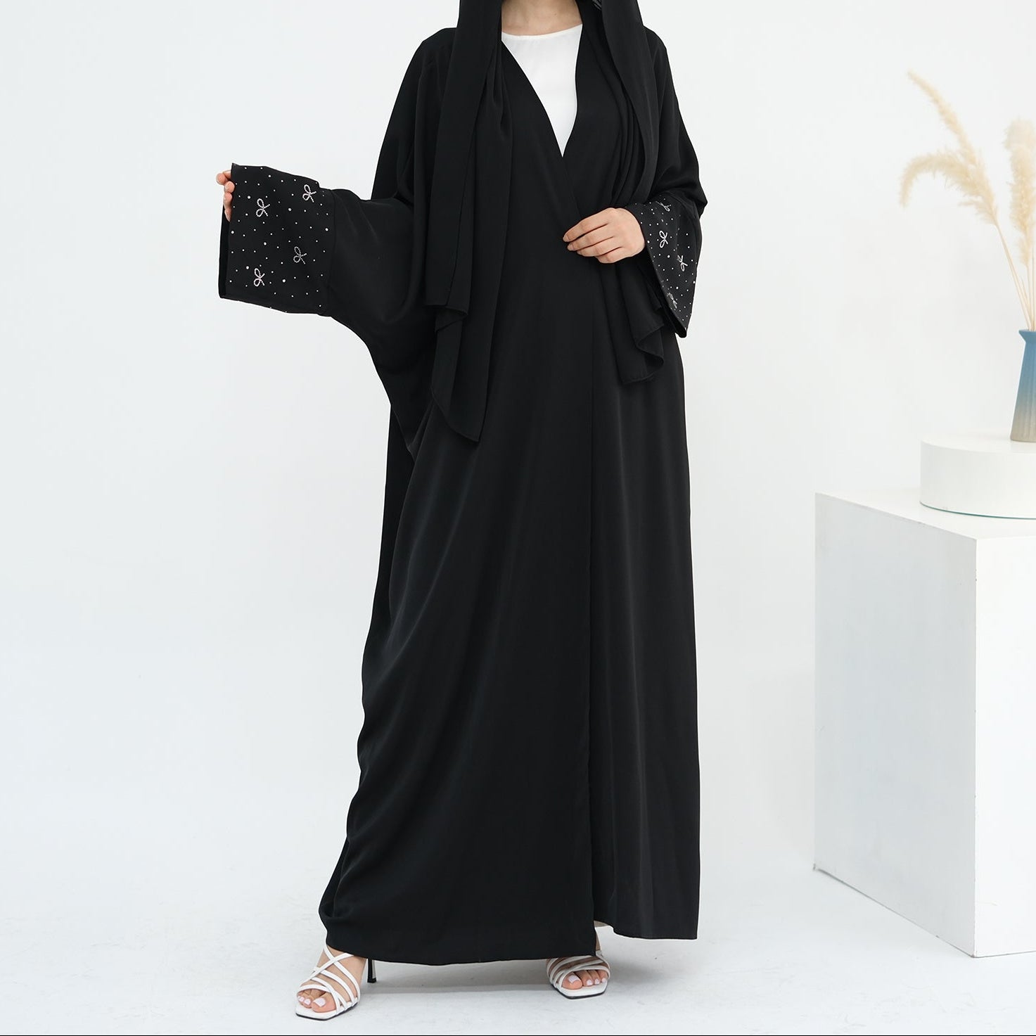 Woman wearing a black abaya with white background. AlLayaliEmbroideredOpenAbaya_Noor_GraceBlack4