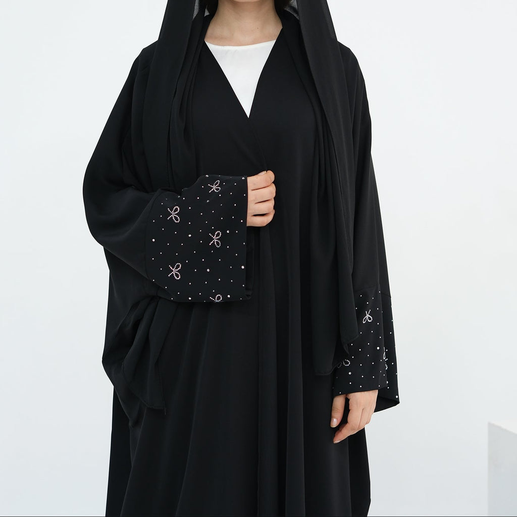 Woman wearing a black abaya with a white background. AlLayaliEmbroideredOpenAbaya_Noor_GraceBlack5