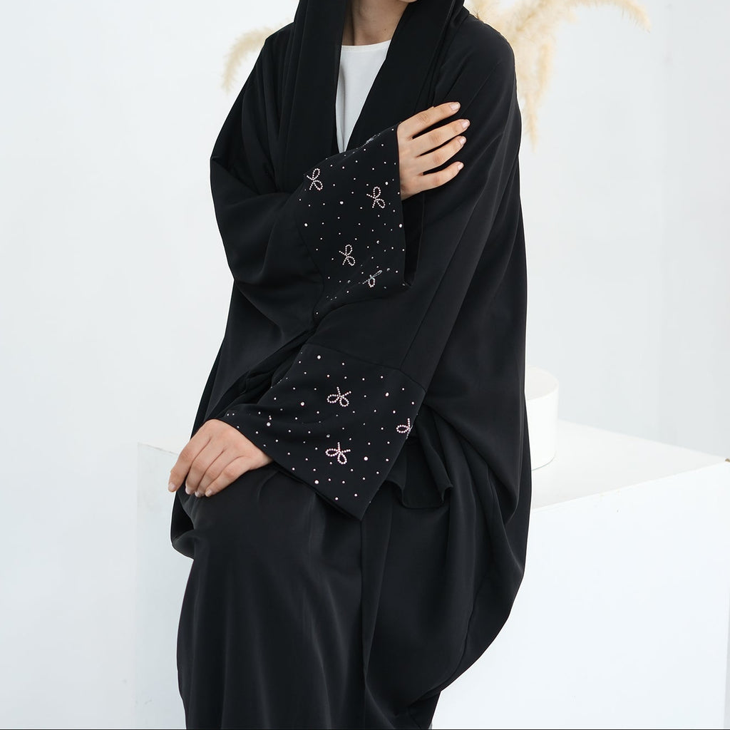 Woman wearing a black abaya with a white background. AlLayaliEmbroideredOpenAbaya_Noor_GraceBlack7