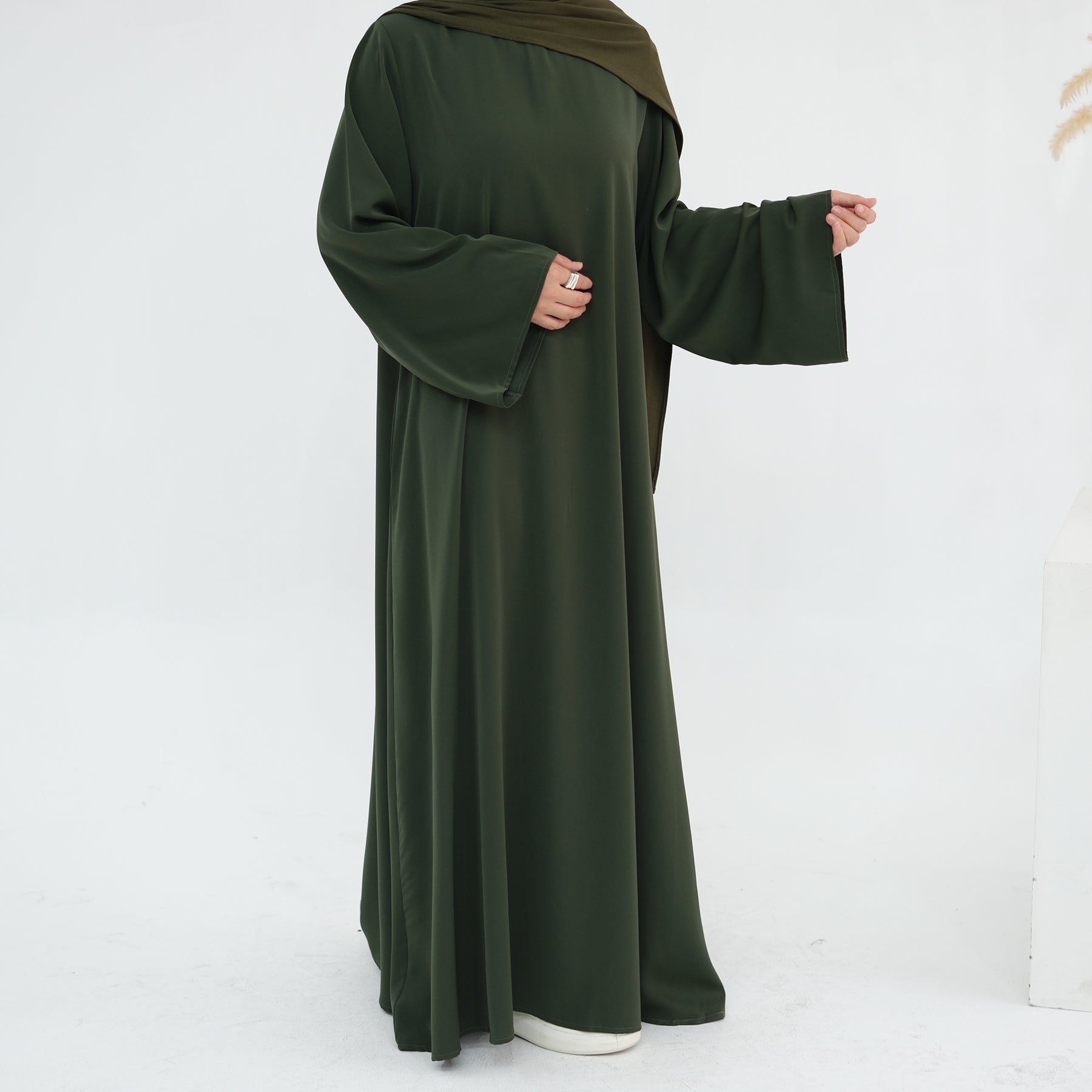Person wearing a long green dress with a white background
