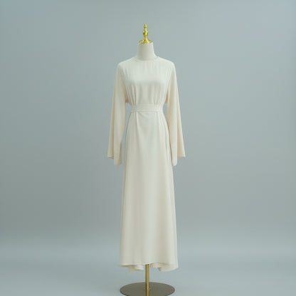 Beige dress on a mannequin against a white paneled wall. AsasAbayaInnerDress_Noor_Grace Beige - Noor & Grae