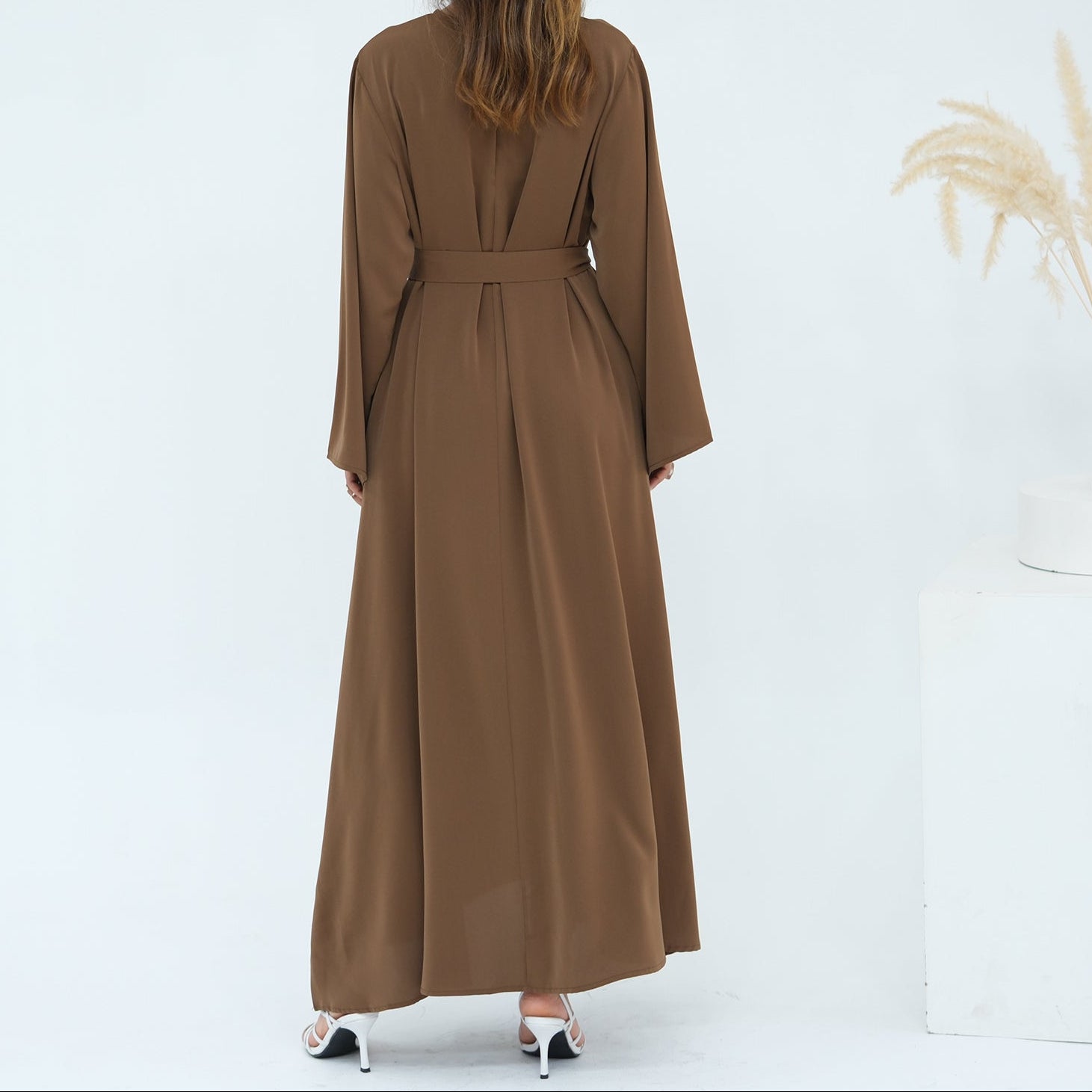 Woman wearing a long brown dress against a white background