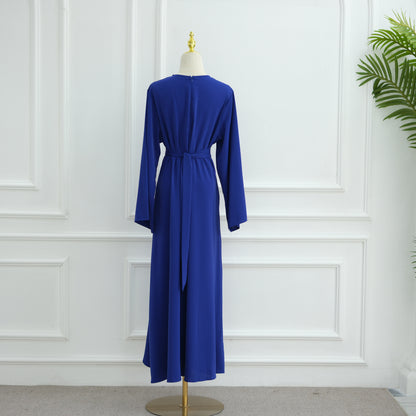 Blue dress on a mannequin against a white paneled wall. AsasAbayaInnerDress_Noor_GraceRoyalBlue - Noor & Grace