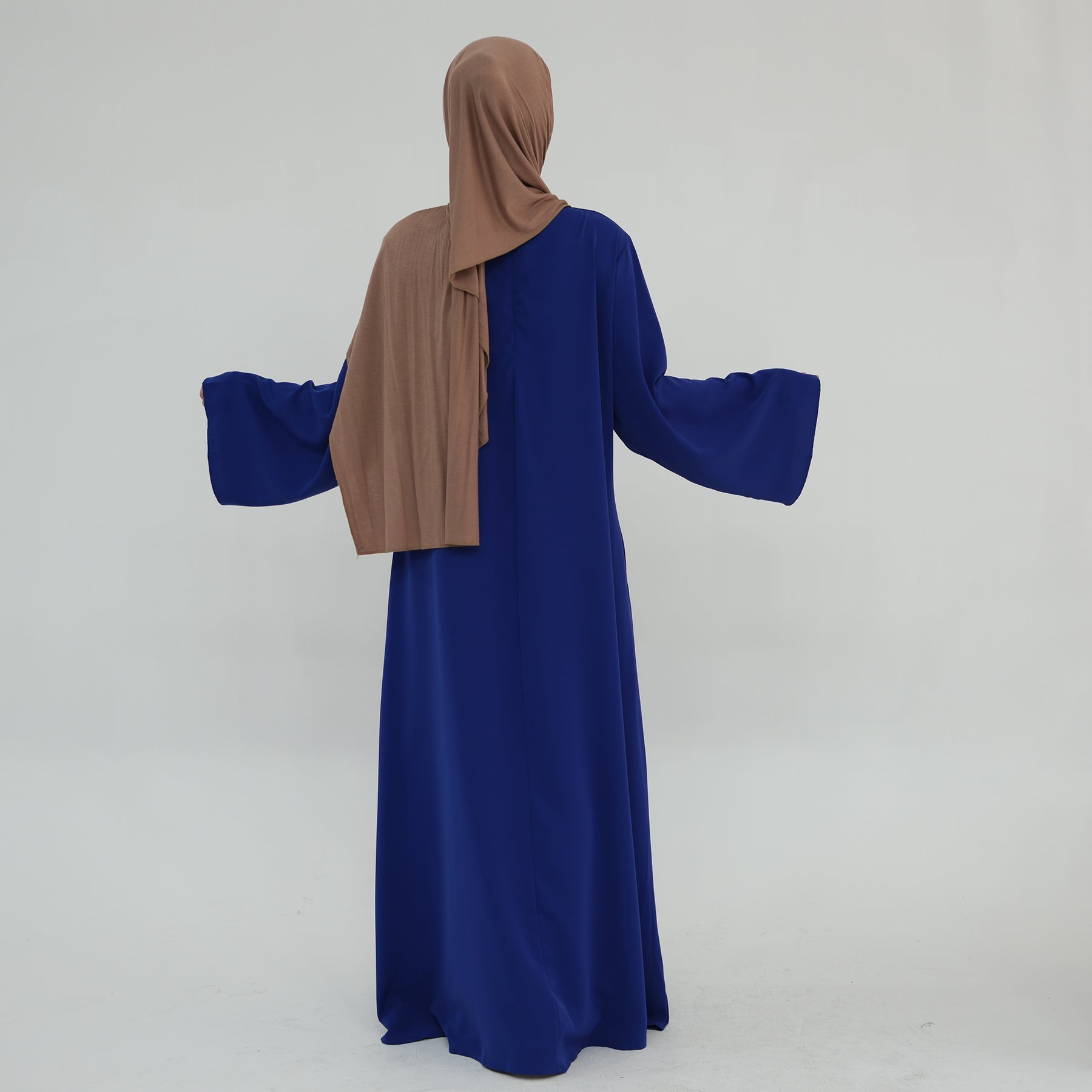 Person wearing a blue dress and brown hijab on a white background