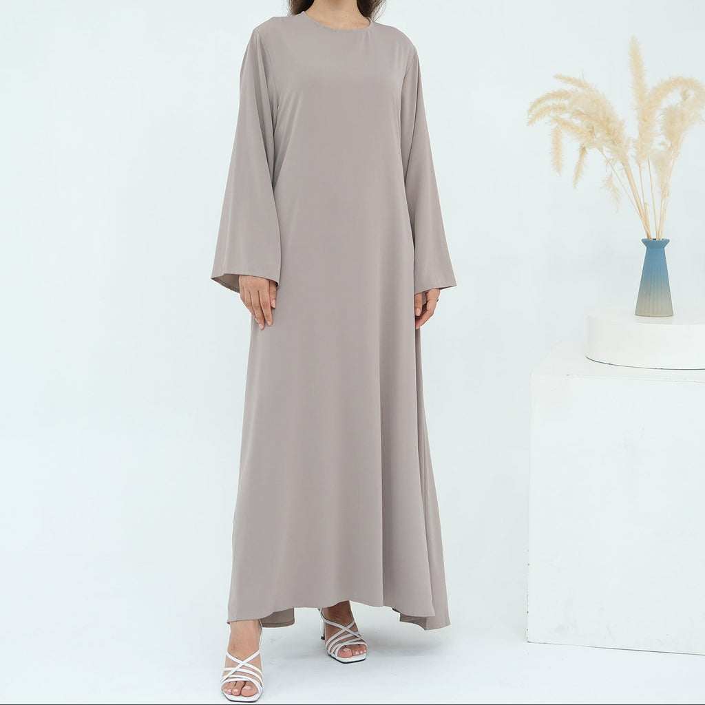 Woman wearing a long beige dress on a white background