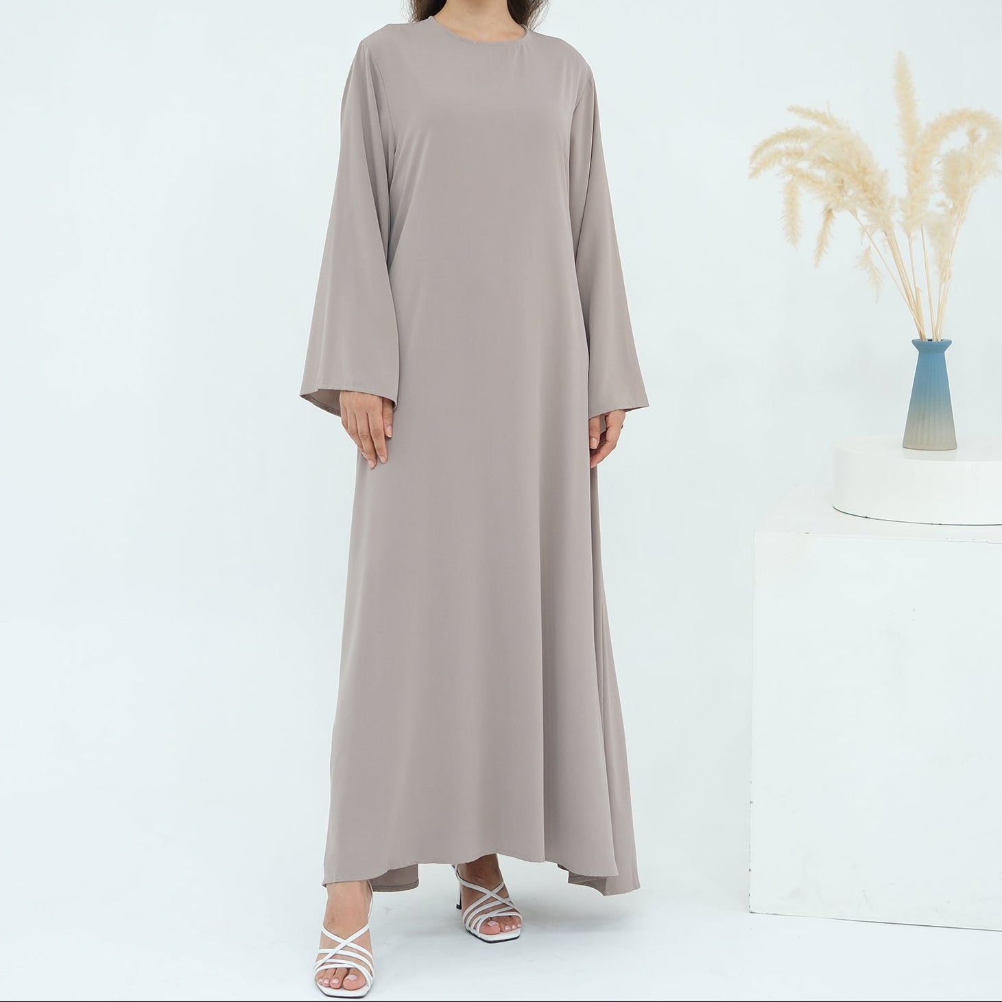 Woman wearing a long beige dress on a white background