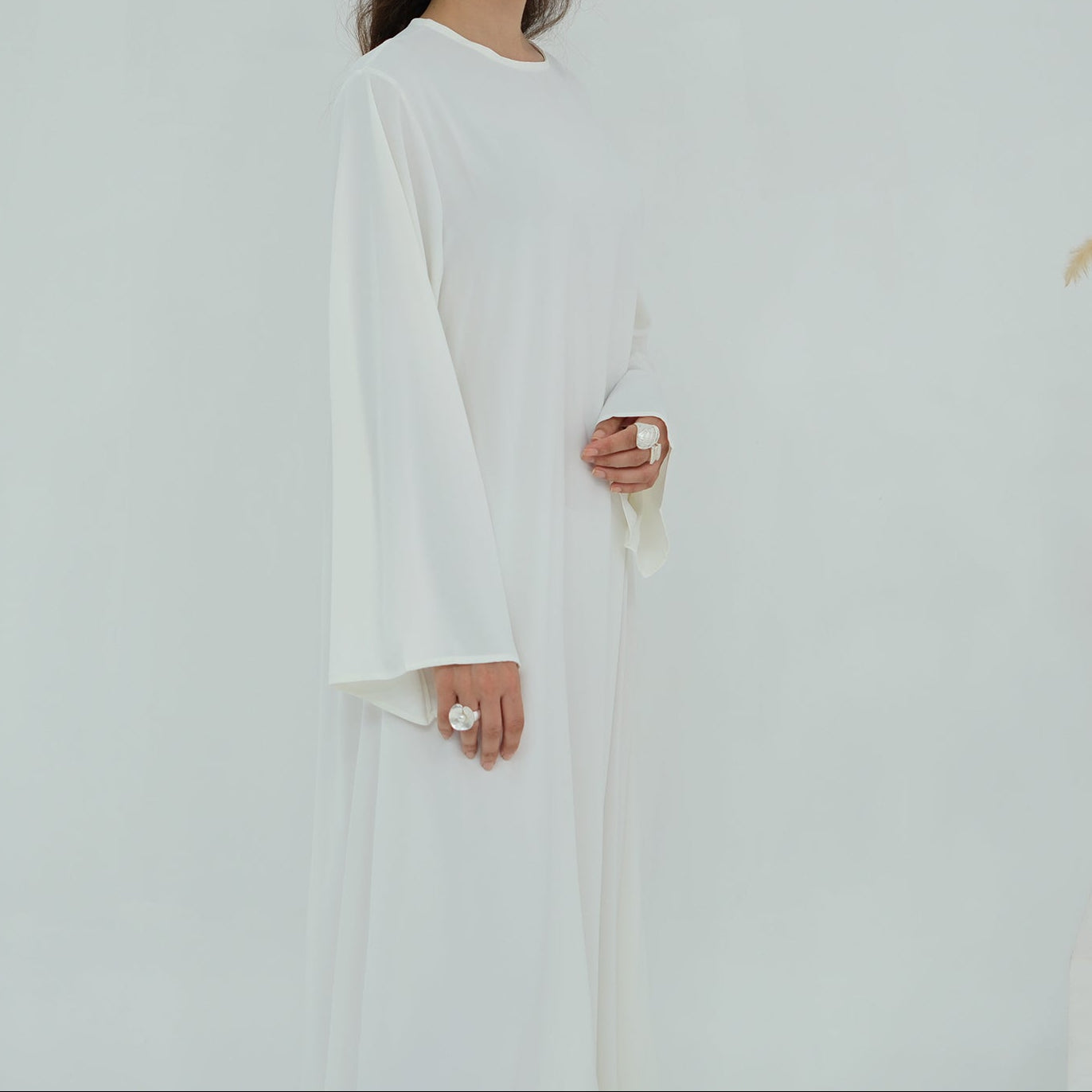 Woman wearing a long white dress against a plain background