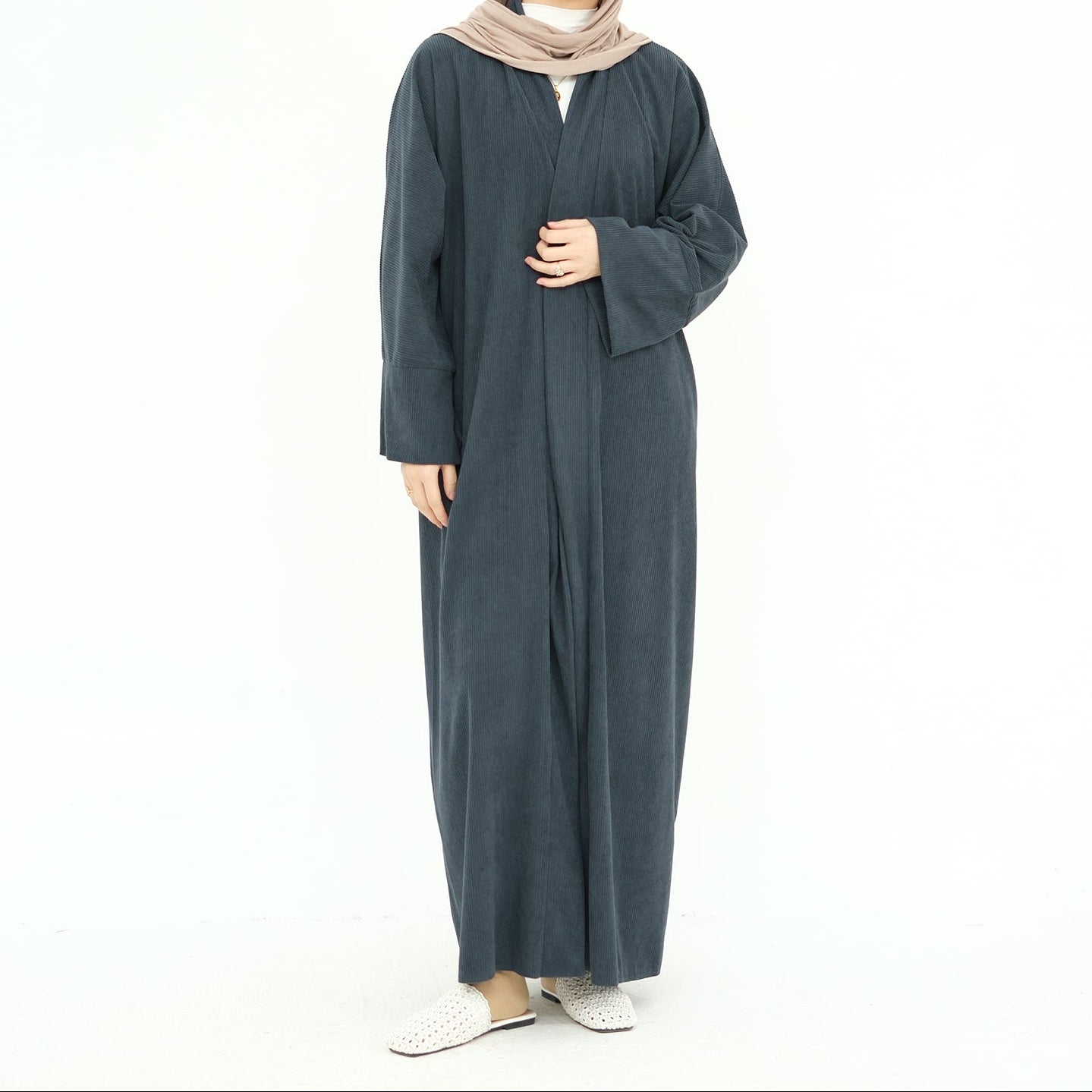 Woman wearing a long dark gray abaya with a beige hijab on a white background. ClassicCorduroyAbaya_Gray1 - Noor & Grace