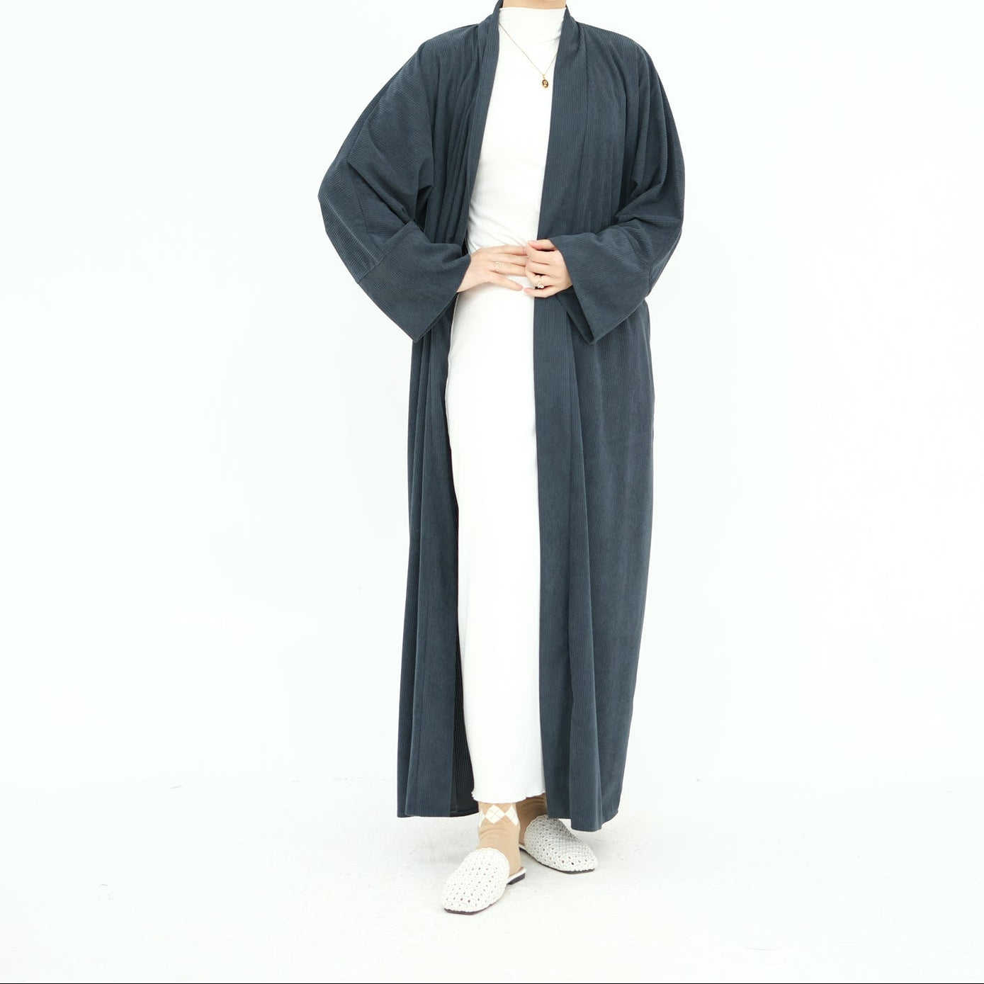 Woman wearing a long dark gray abaya with a beige hijab on a white background. ClassicCorduroyAbaya_Gray2 - Noor & Grace
