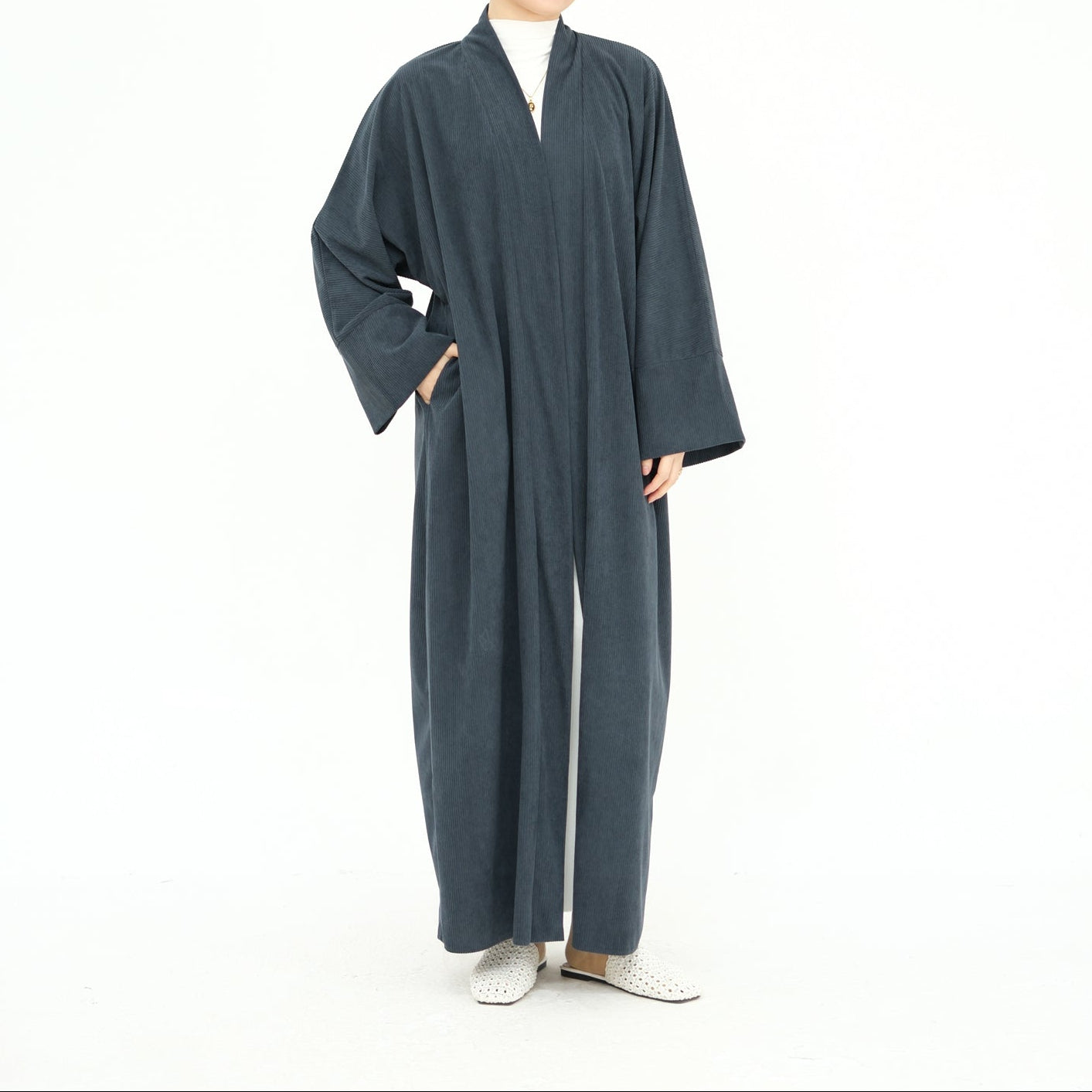 Woman wearing a long dark gray abaya with a beige hijab on a white background. ClassicCorduroyAbaya_Gray2 - Noor & Grace