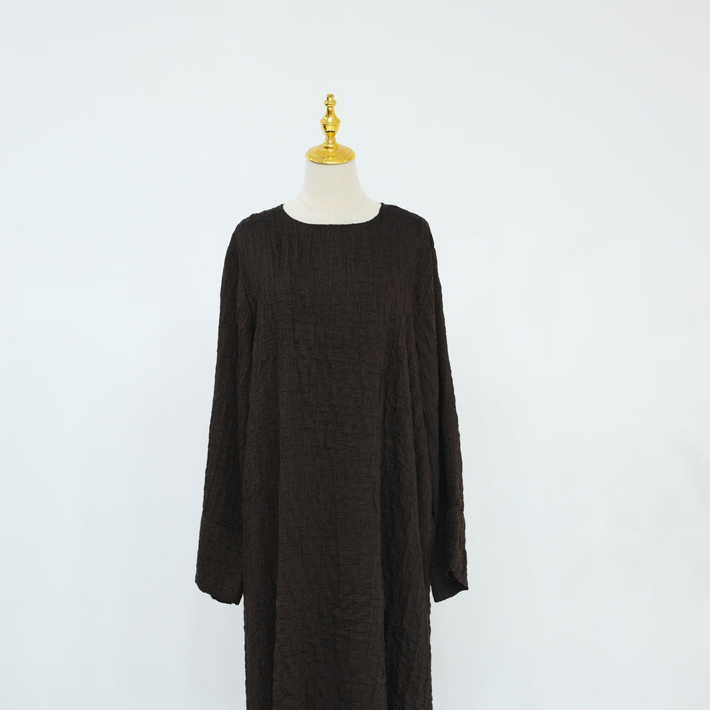 Person wearing a dark brown abaya outfit with a matching headscarf, holding a beige handbag. Dubai_Luxe_2026_Abaya_2026_Coffee_8 - Noor & Grace