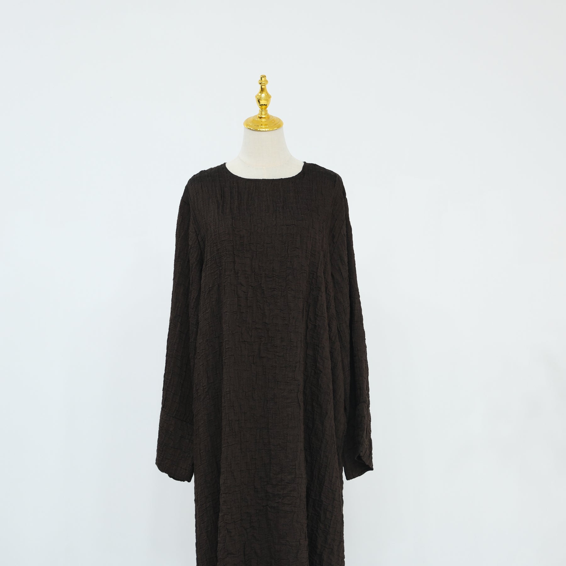 Person wearing a dark brown abaya outfit with a matching headscarf, holding a beige handbag. Dubai_Luxe_2026_Abaya_2026_Coffee_8 - Noor & Grace