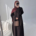 Person wearing a dark brown abaya outfit with a matching headscarf, holding a beige handbag. Dubai_Luxe_2026_Abaya_2026_Coffee_8 - Noor & Grace