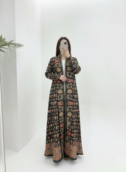 Person wearing a long, patterned coat against a white background. Al Noor Pleated Abaya Multi – 2025 Dubai Edition (عباءة النور بليت – إصدار دبي 2025) - Noor & Grace