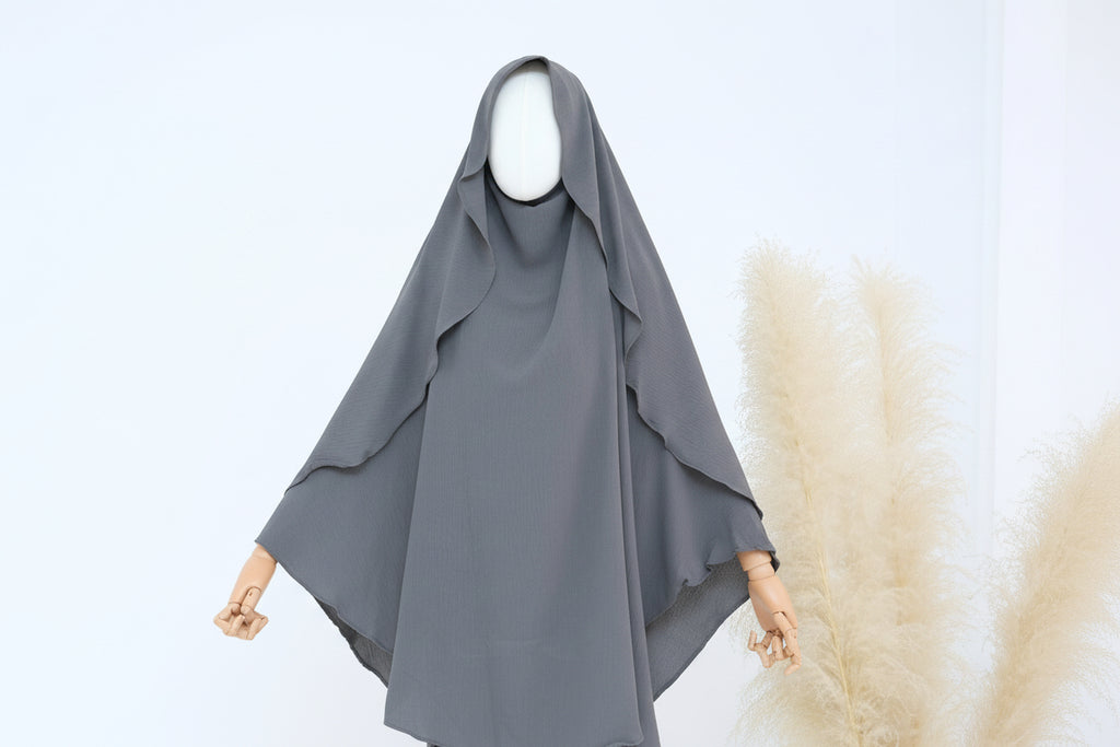 Gray hijab on a mannequin with a white background and pampas grass decor.