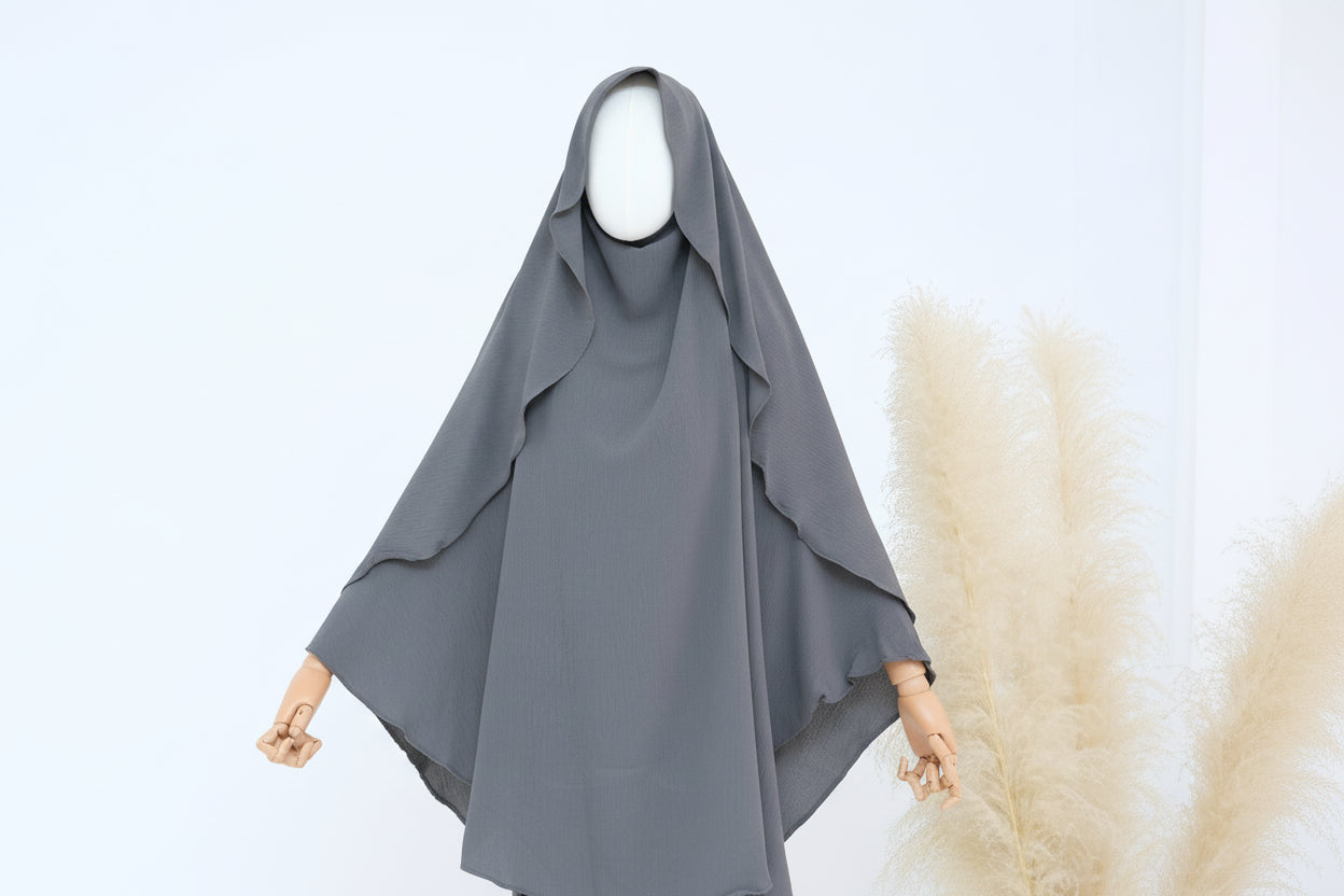 Gray hijab on a mannequin with a white background and pampas grass decor.