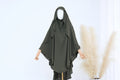 Green hijab on a mannequin with a white background and pampas grass decoration.