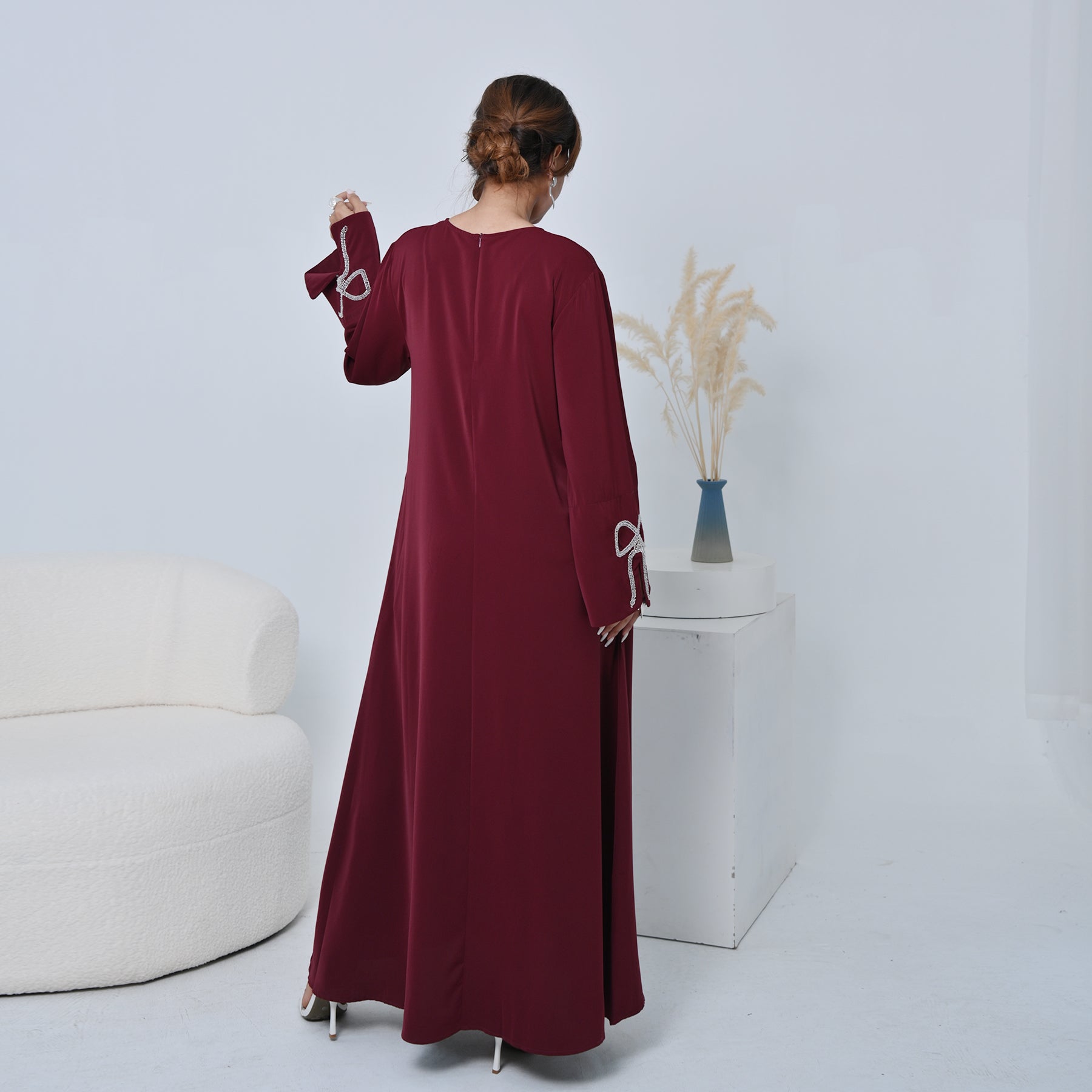 Woman wearing a burgundy dress with white accents in a minimalistic setting.