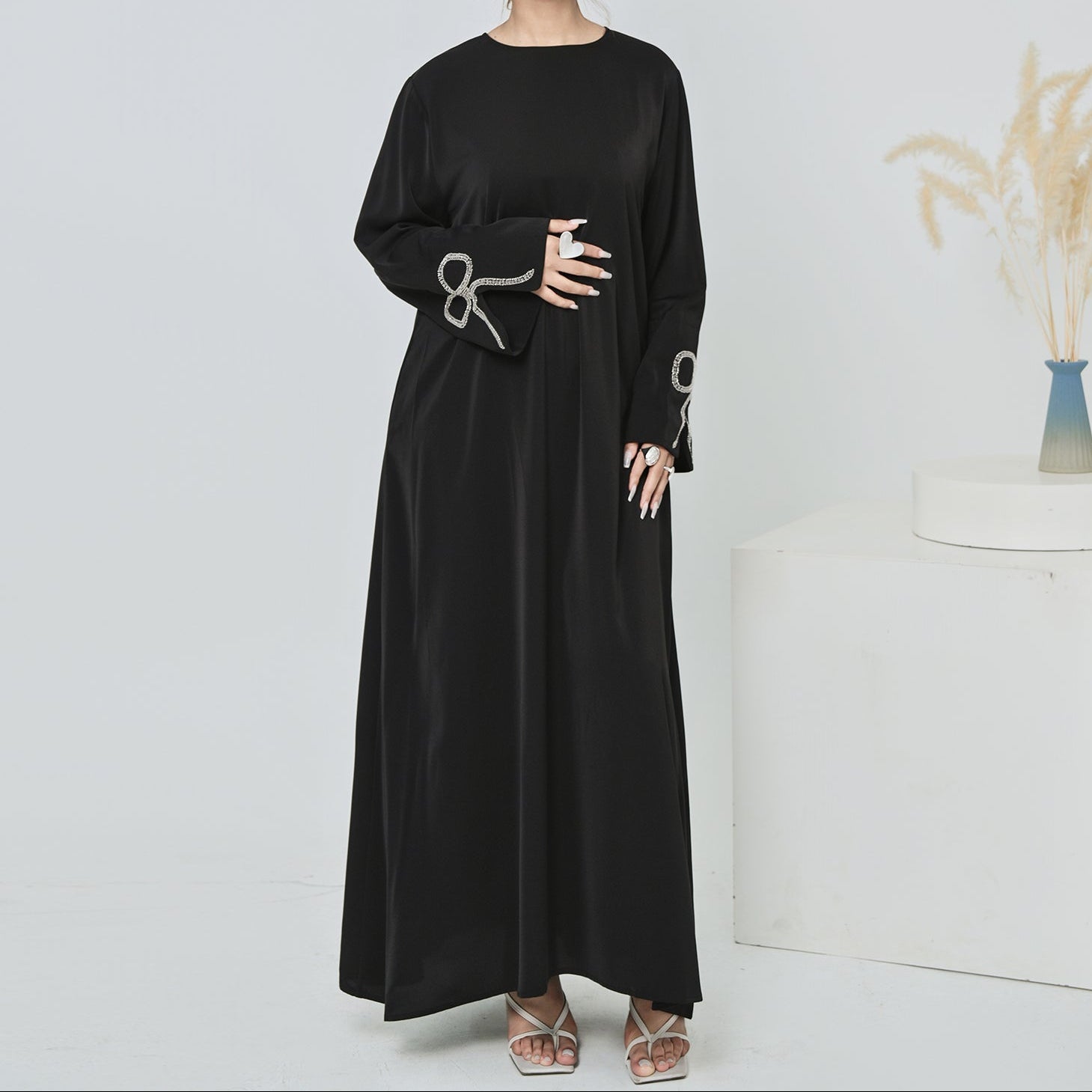 Woman wearing a black dress with long sleeves against a white background