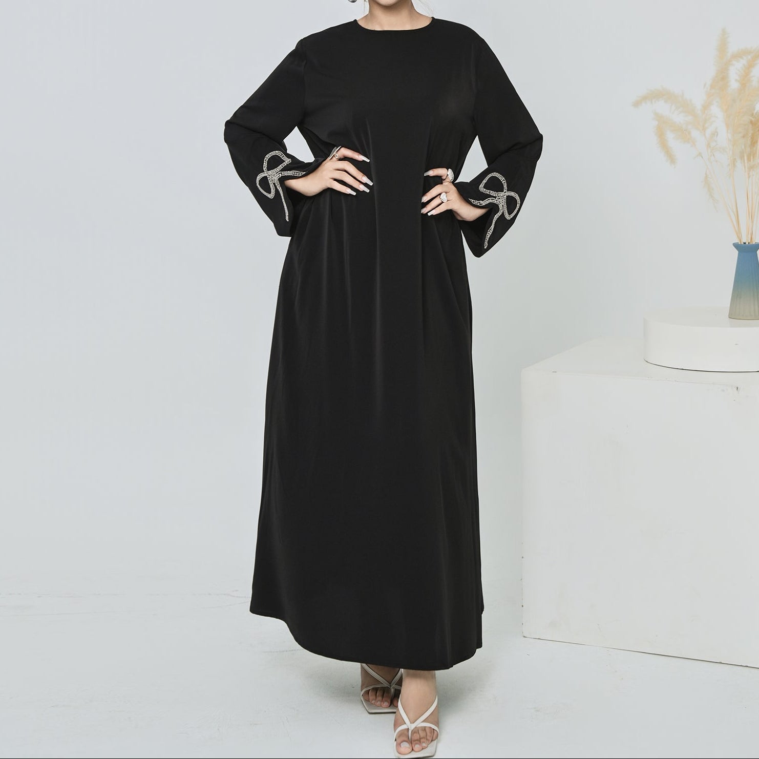 Woman wearing a black dress with decorative sleeves against a white background