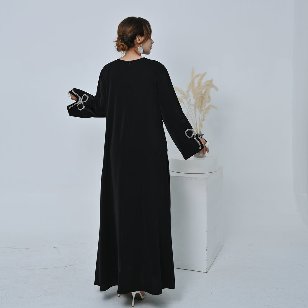 Woman wearing a black long-sleeve dress holding a bouquet of flowers against a white background