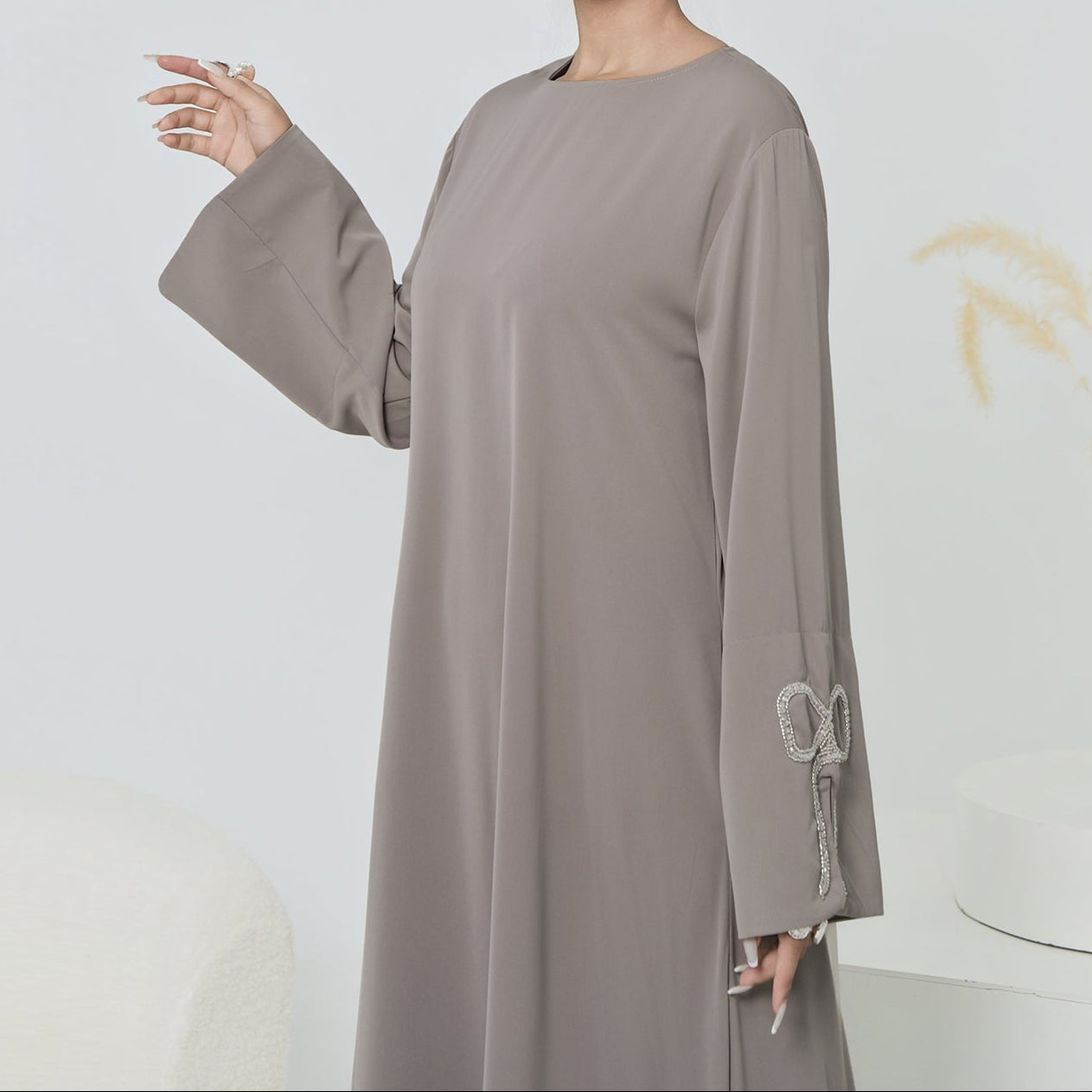 Woman wearing a long, light gray dress with a white background