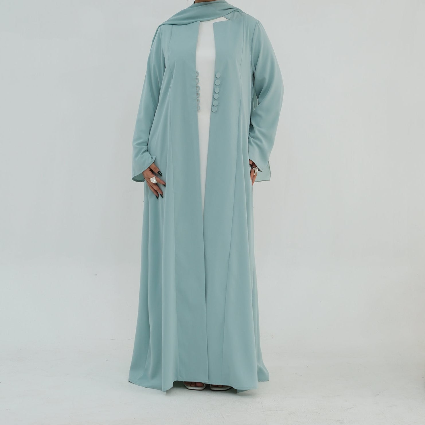 Woman wearing a light blue abaya with a white top on a white background