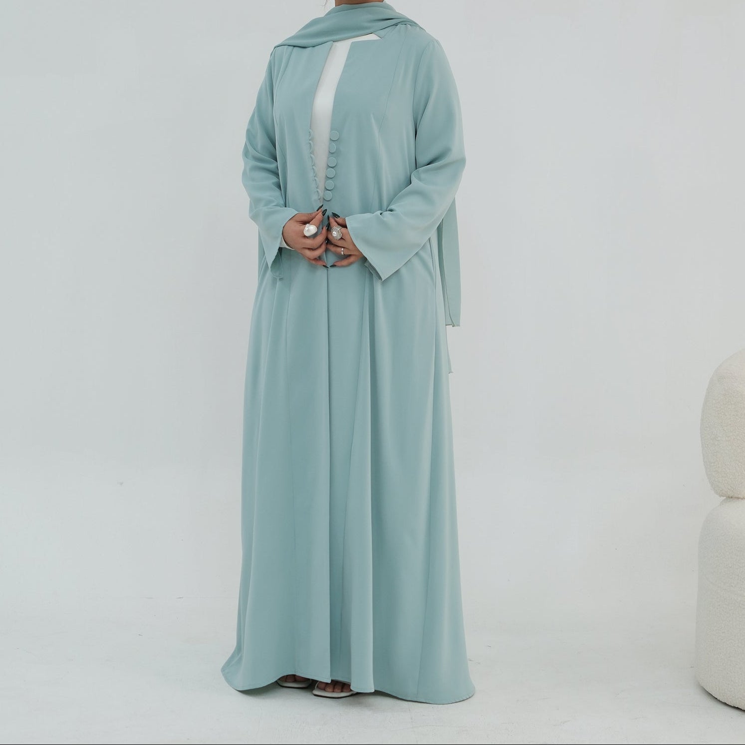 Woman wearing a light blue abaya on a white background