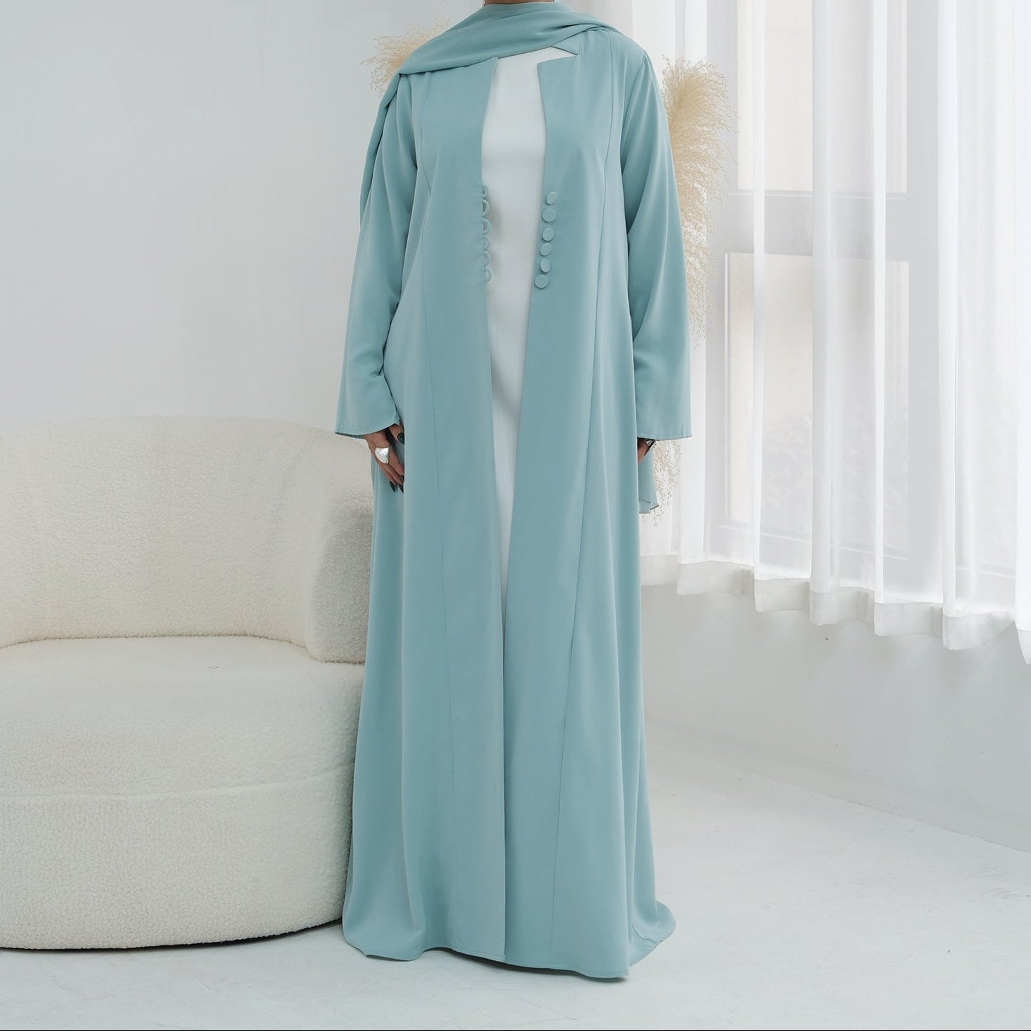 Woman wearing a light blue abaya in a white room