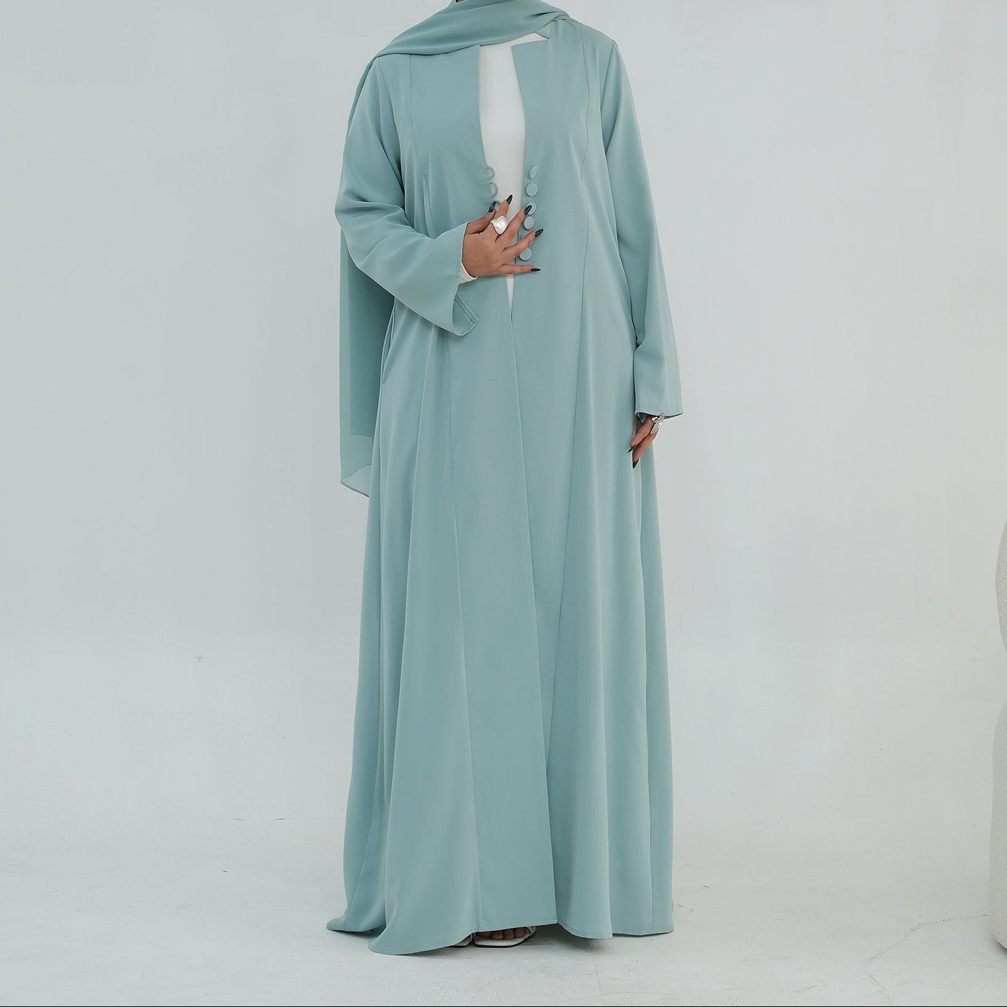 Woman wearing a light blue abaya on a white background