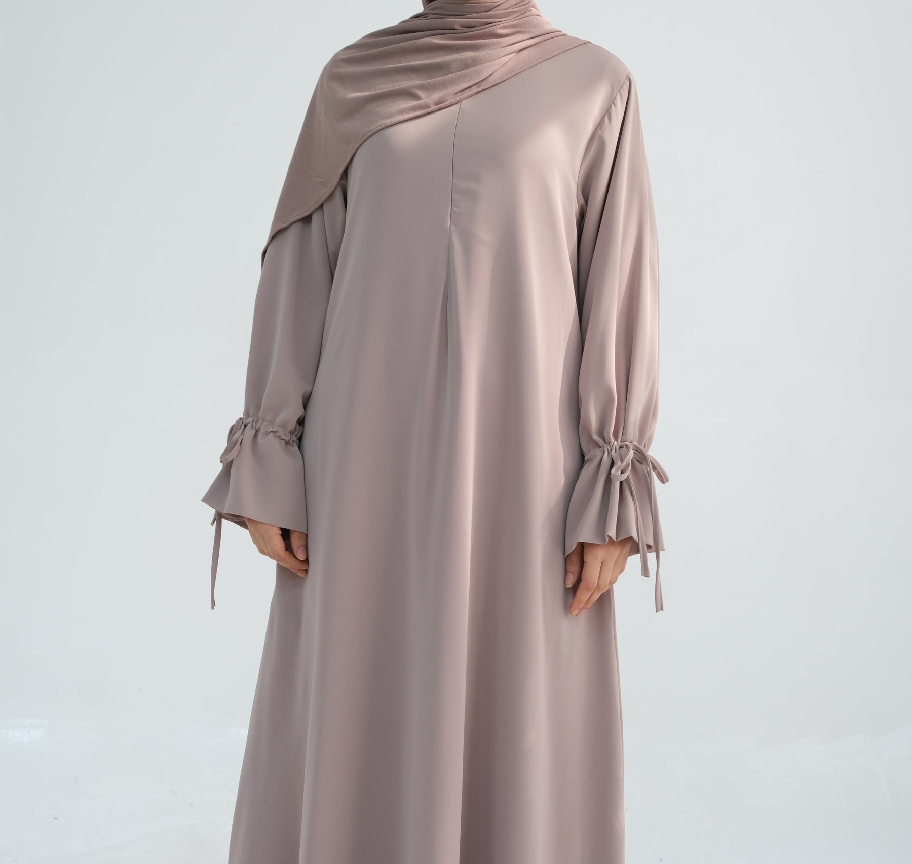Mauve abaya with long sleeves and a hood on a light gray background