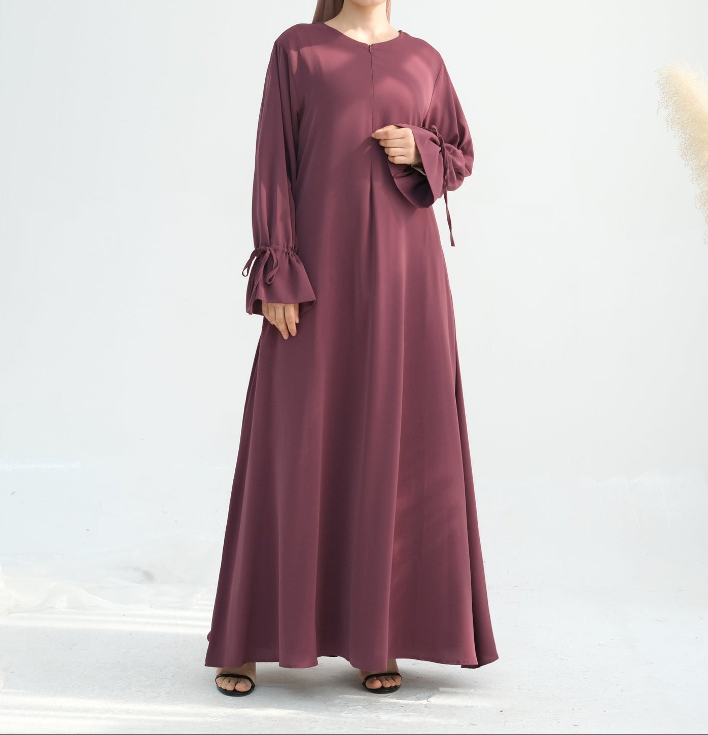 Woman wearing a long burgundy dress on a white background