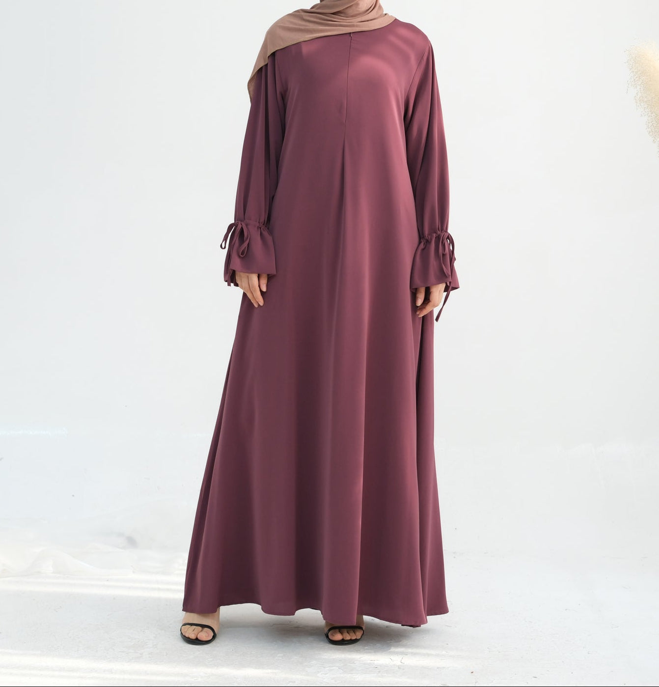 Woman wearing a long burgundy dress on a white background