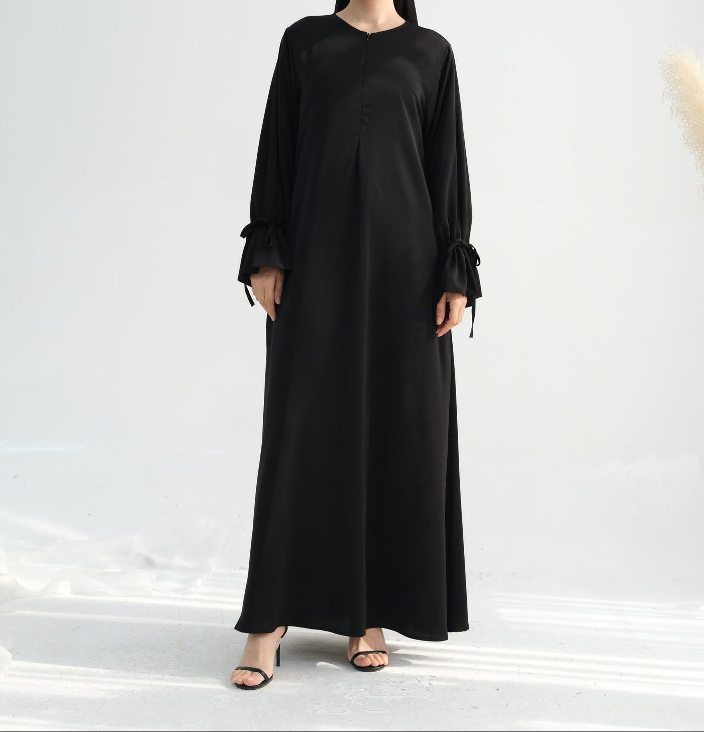 Woman wearing a black dress with long sleeves on a white background