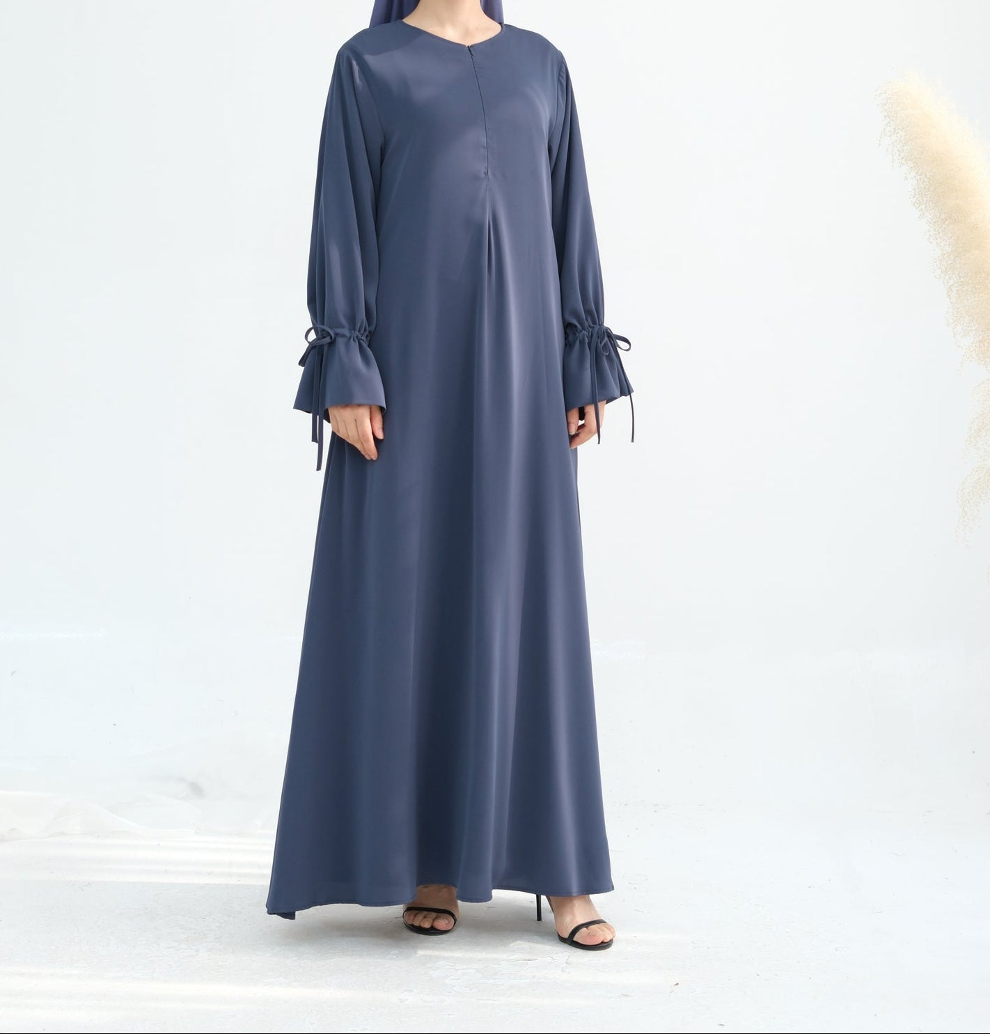 Woman wearing a long blue dress with ruffled sleeves on a white background