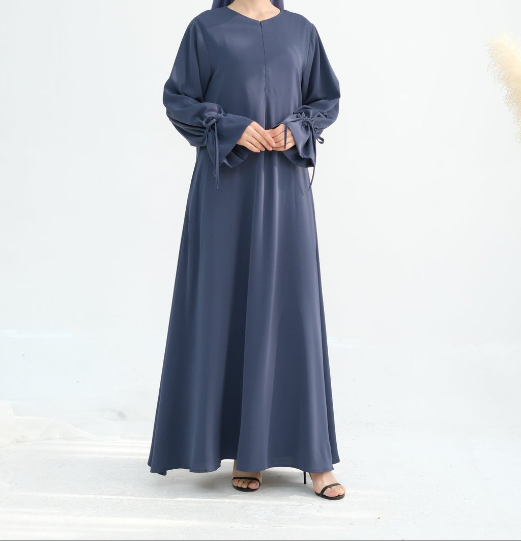 Woman wearing a long blue dress with a matching headscarf on a white background