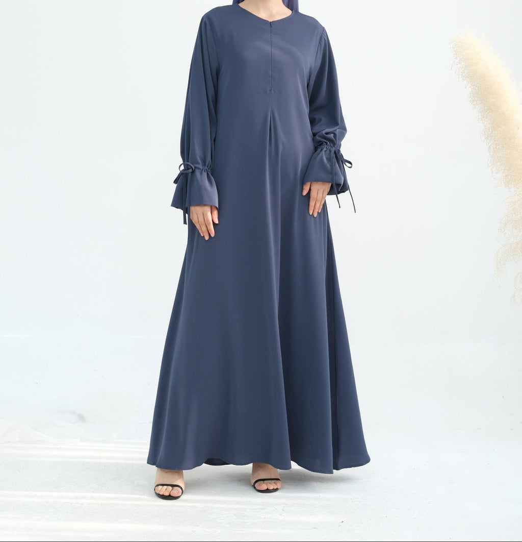 Woman wearing a long blue dress with ruffled sleeves on a white background