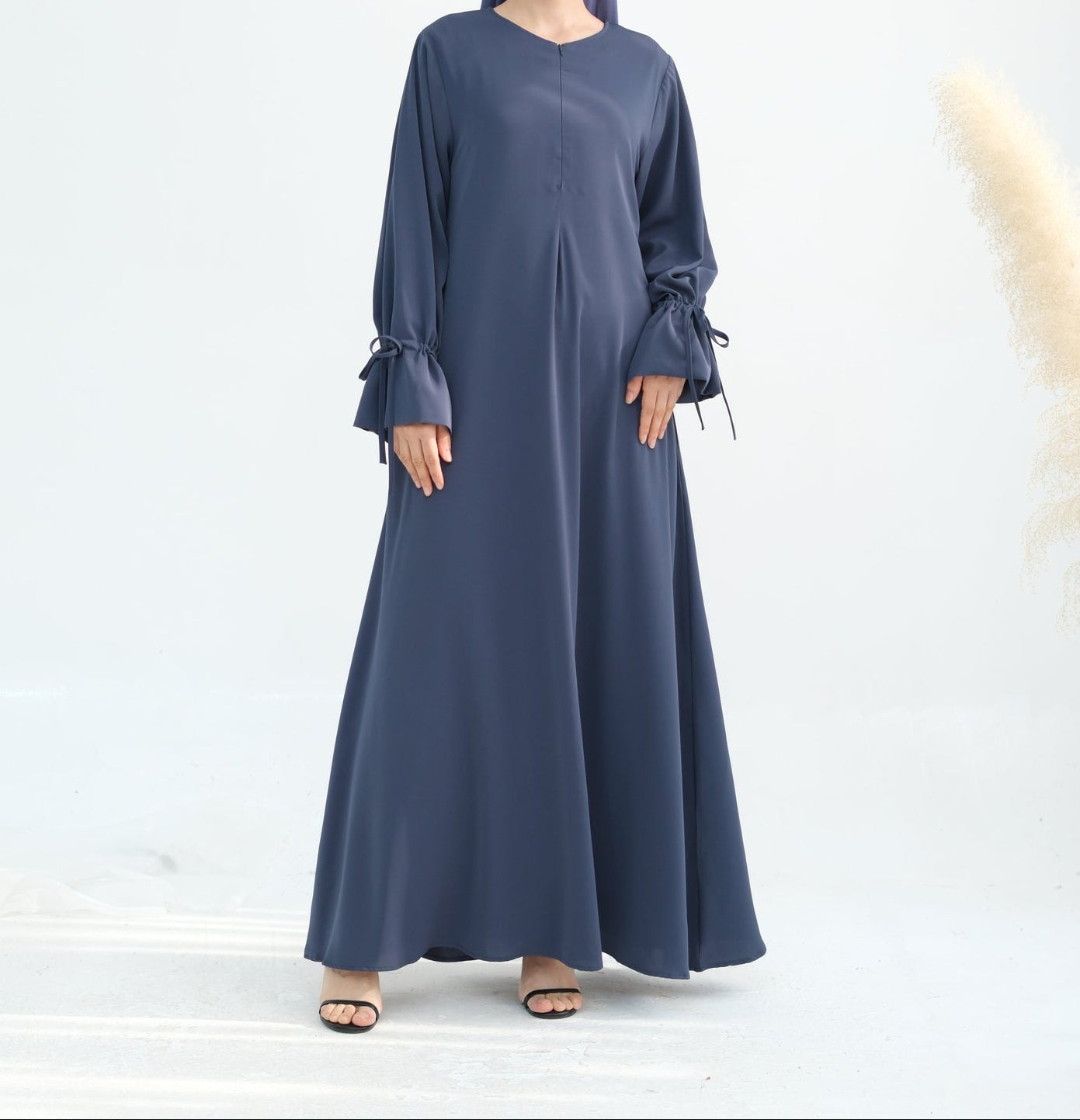 Woman wearing a long blue dress with ruffled sleeves on a white background