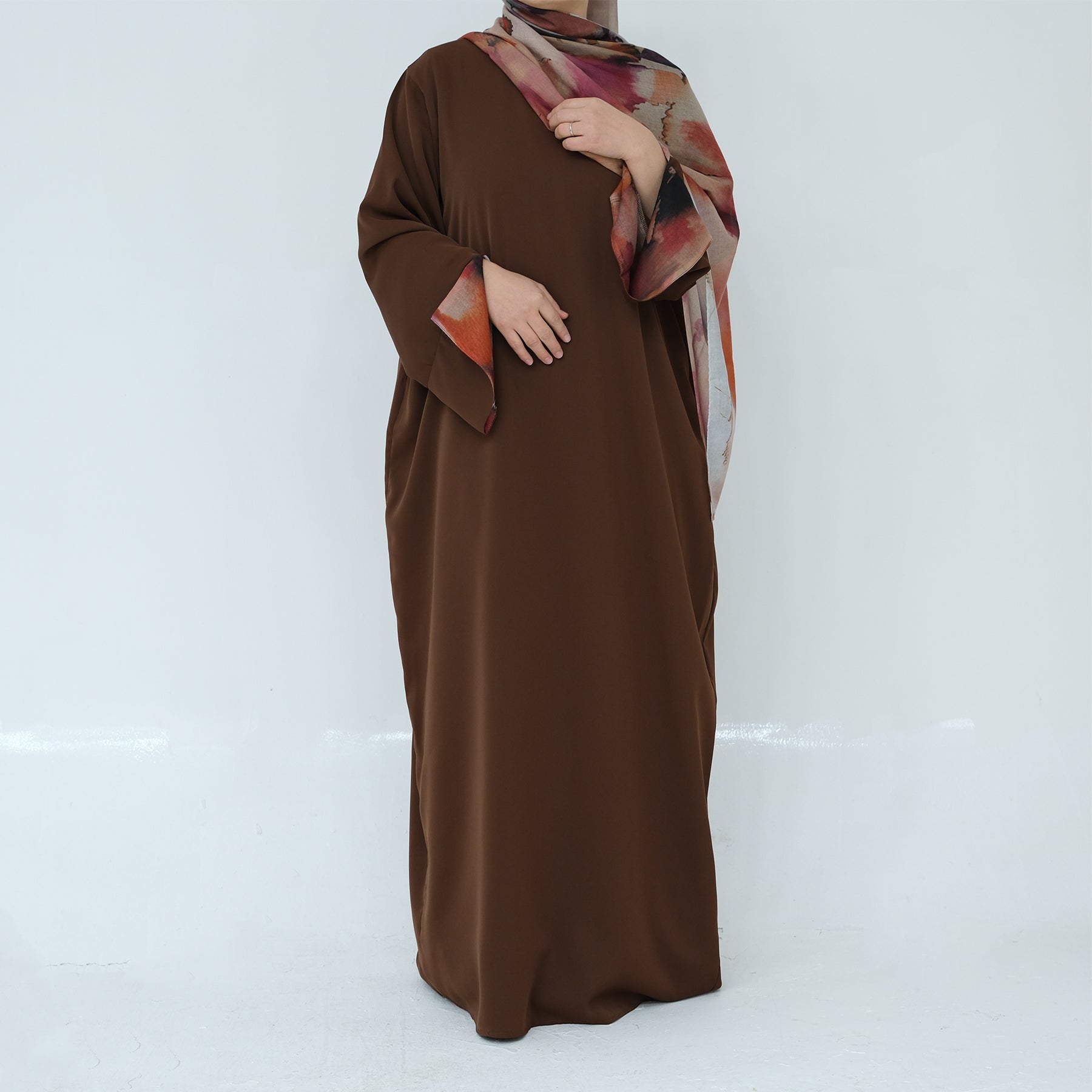Brown abaya with a patterned shawl on a white background
