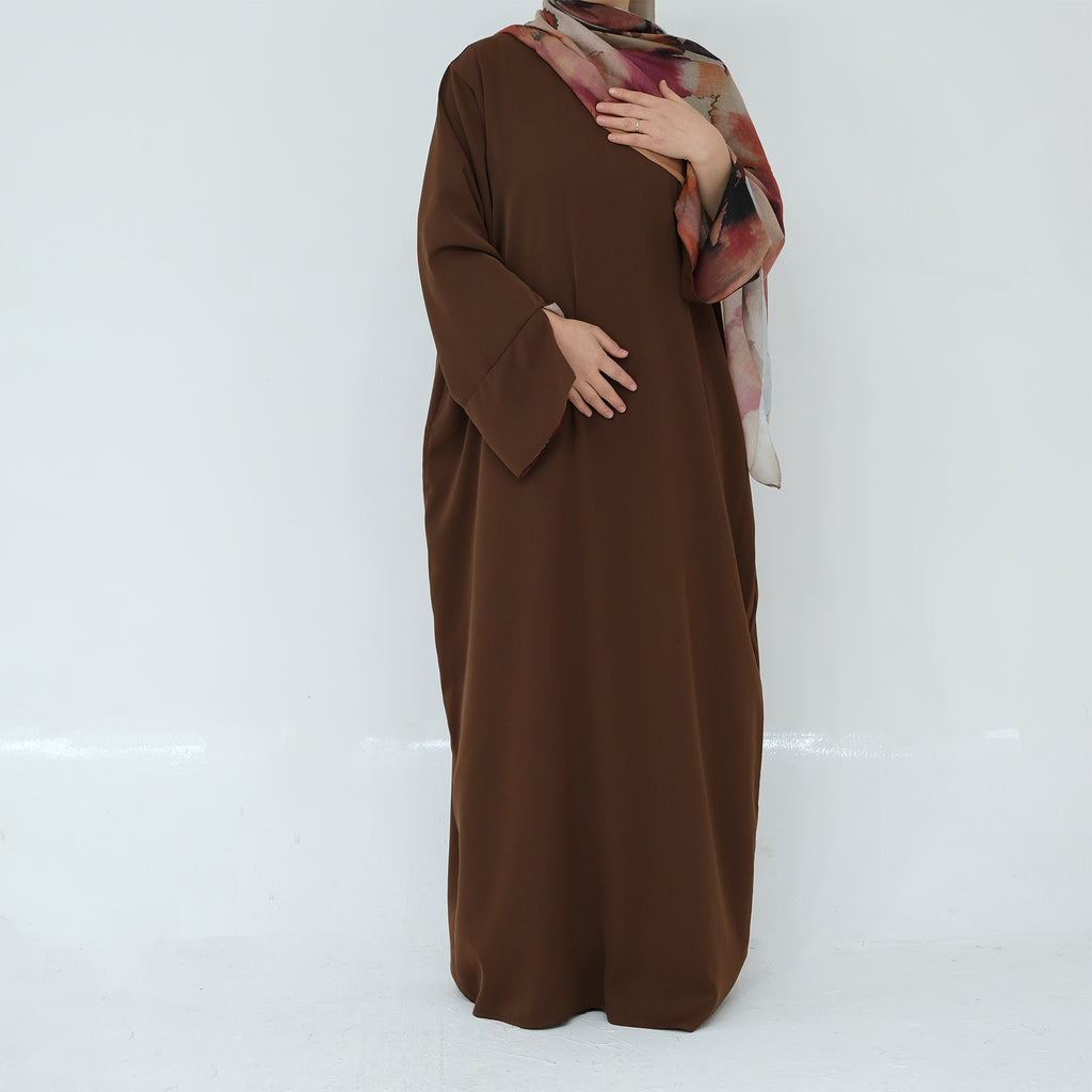 Brown abaya worn by a person on a white background