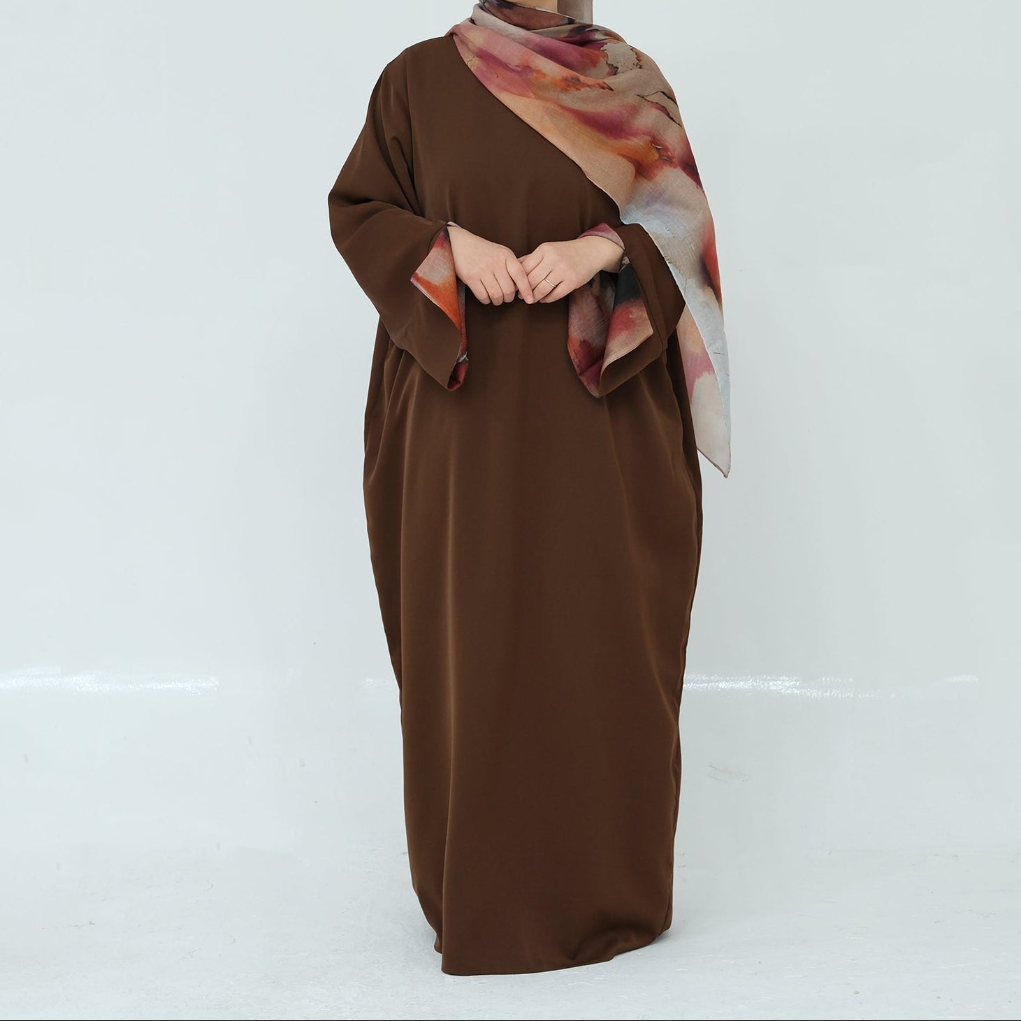 Woman wearing a brown dress with a patterned scarf on a white background