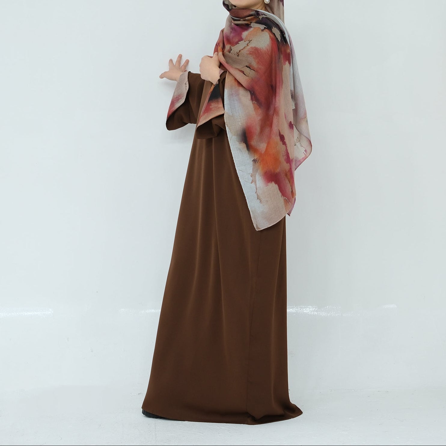 Woman wearing a brown dress and patterned scarf on a white background